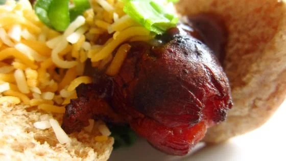 Close-up of a taco with a beef patty, shredded cheese, chopped green onions, and a shell.