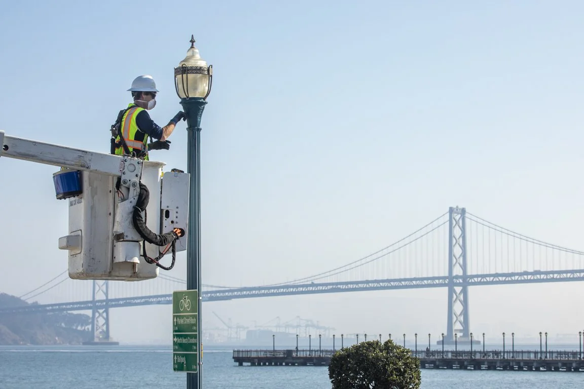 Worker in a bucket truck servicing a streetlight near the Bay Bridge.