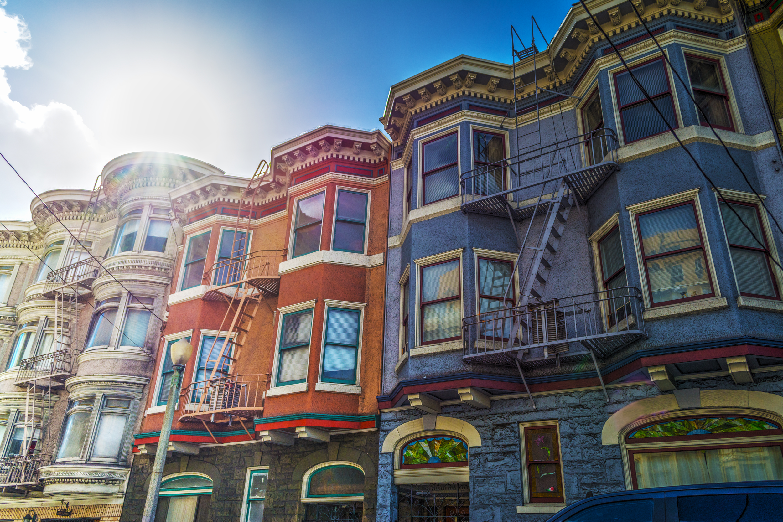 Colorful San Francisco apartment buildings with bay windows and fire escapes.