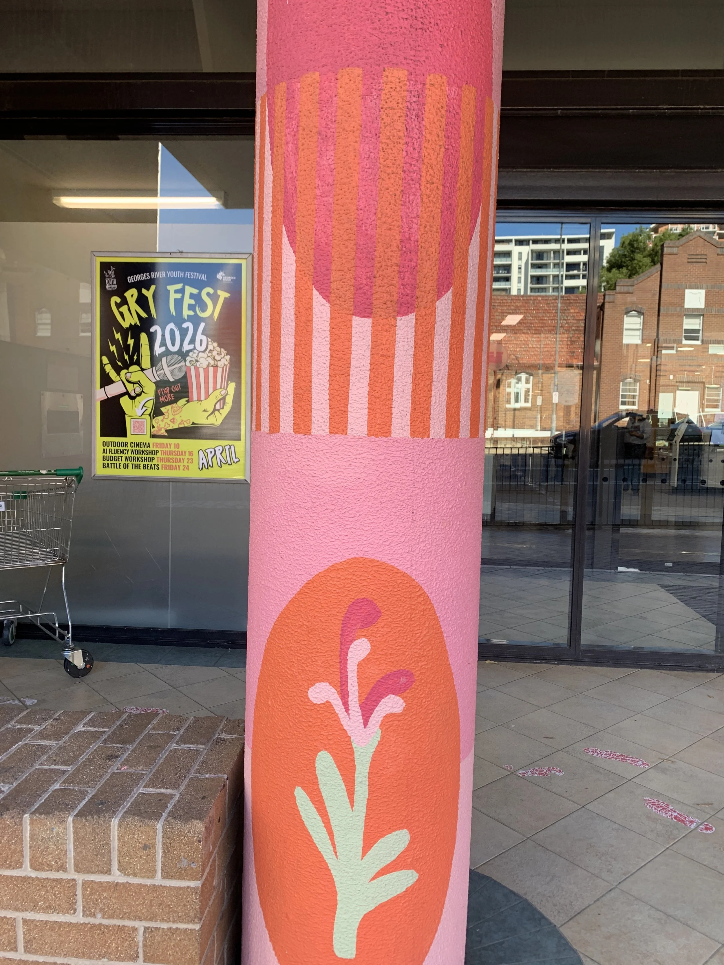 Decorative pink column with a stylized flower design in pink, orange, and green, positioned outside the Hurstville Library.