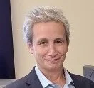 A middle-aged woman with short gray hair, wearing a dark blazer, smiling.
