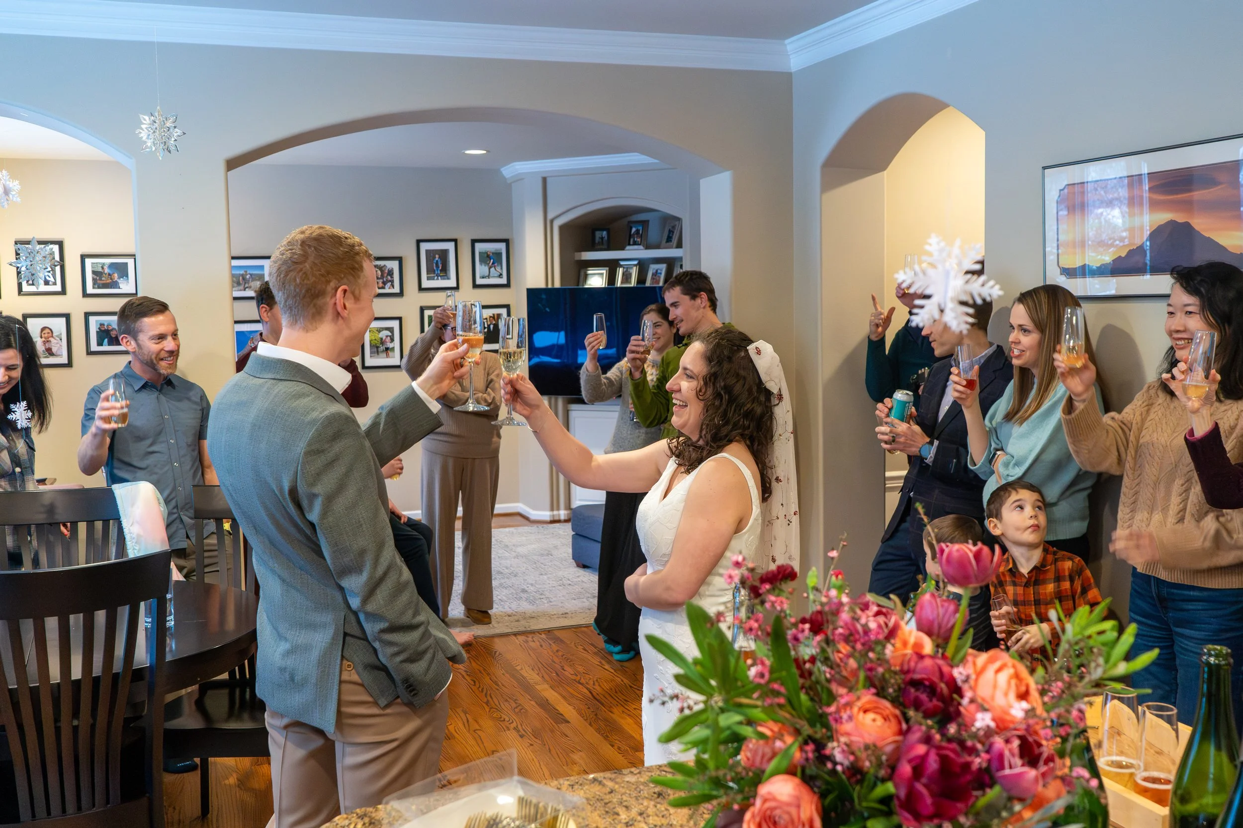 A bride and groom hold a champagne toast with family and friends during their hybrid wedding, which included backcountry skiing at Snoqualmie Pass followed by a living room ceremony and reception at home.