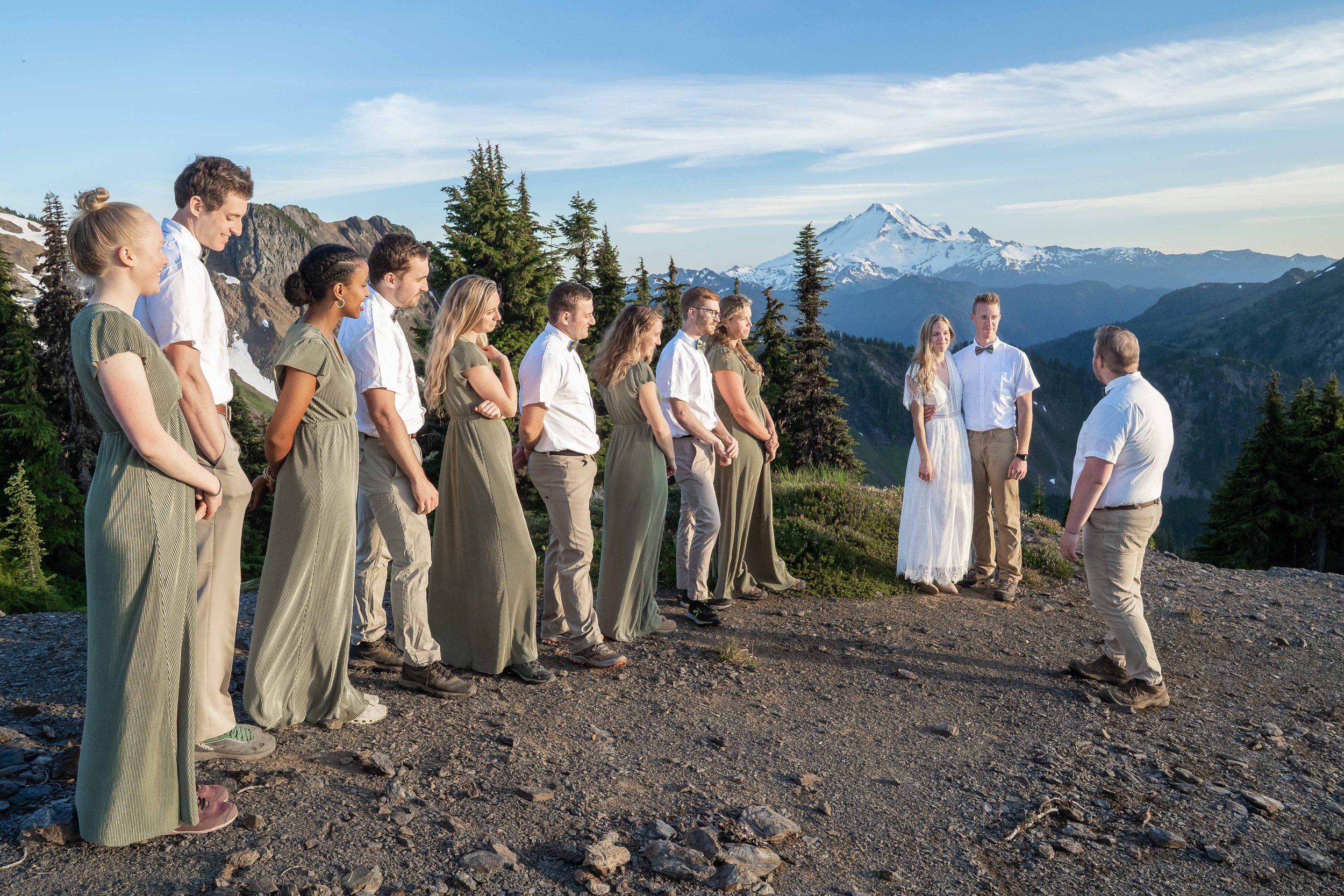 A photo of a wedding party standing next to a couple during an elopement ceremony at High Pass in the North Cascades, with Mt. Baker visible in the background.