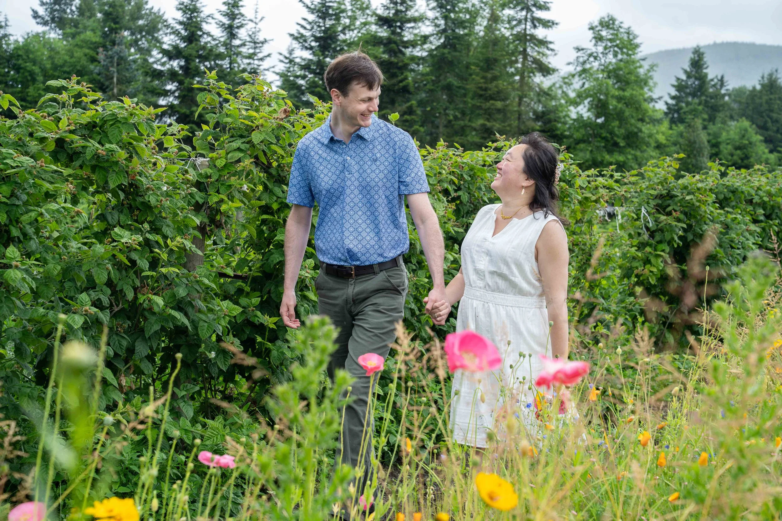 A couple holding hands and walking through a field of flowers during a Bellingham elopement photography session.
