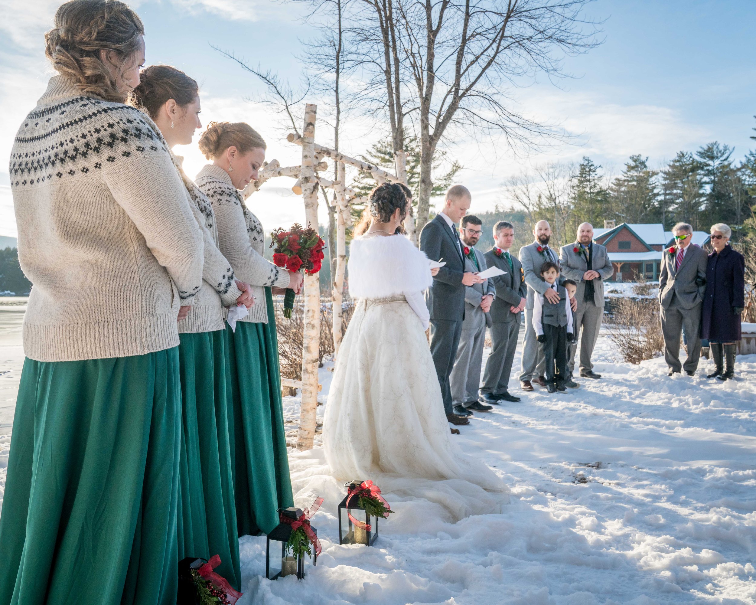 A photo of a bride, groom, bridesmaids, and groomsmen standing at an altar in the snow during a wedding ceremony.