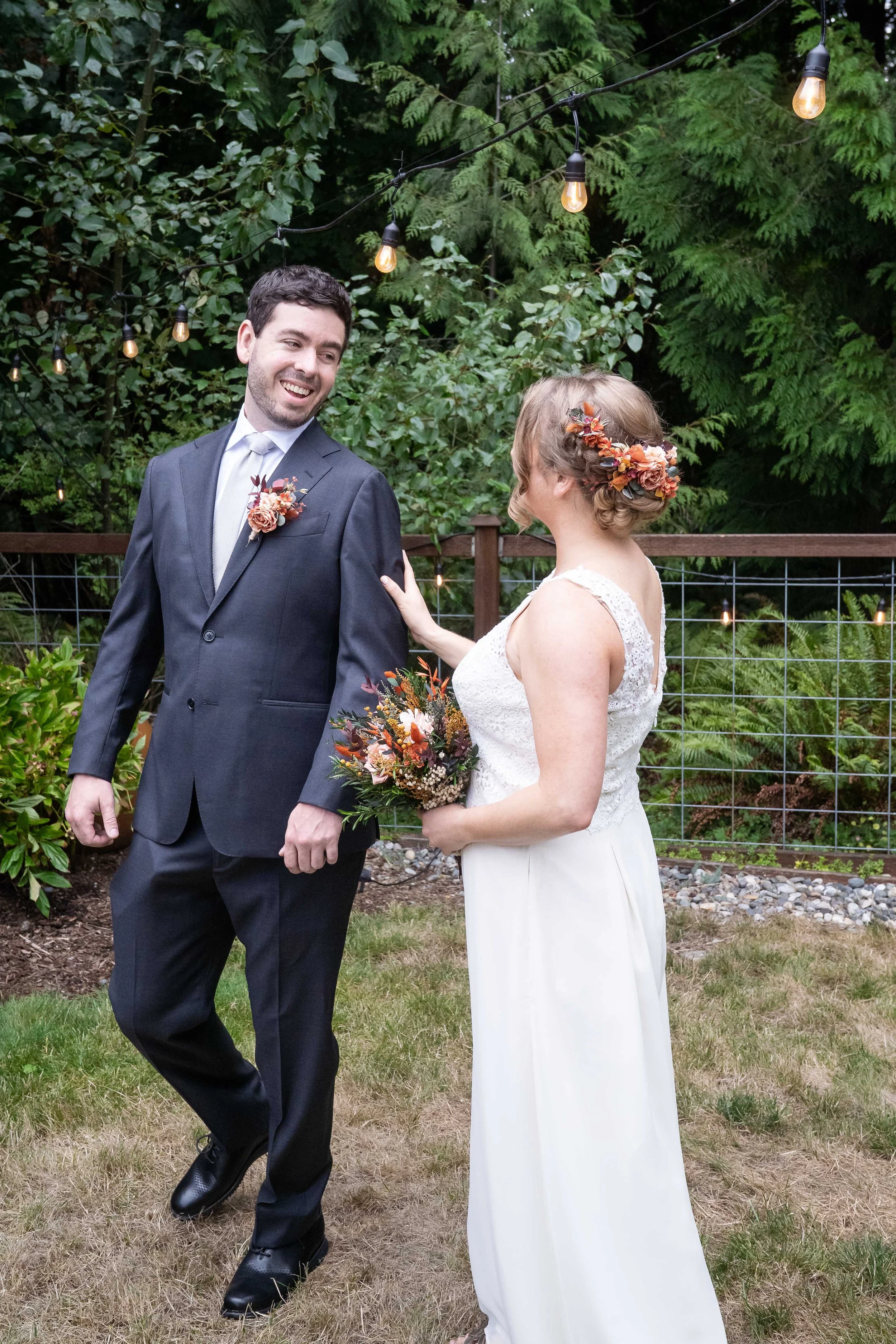 A photo of a backyard first look captured as the groom turns and sees the bride in her wedding dress for the first time.