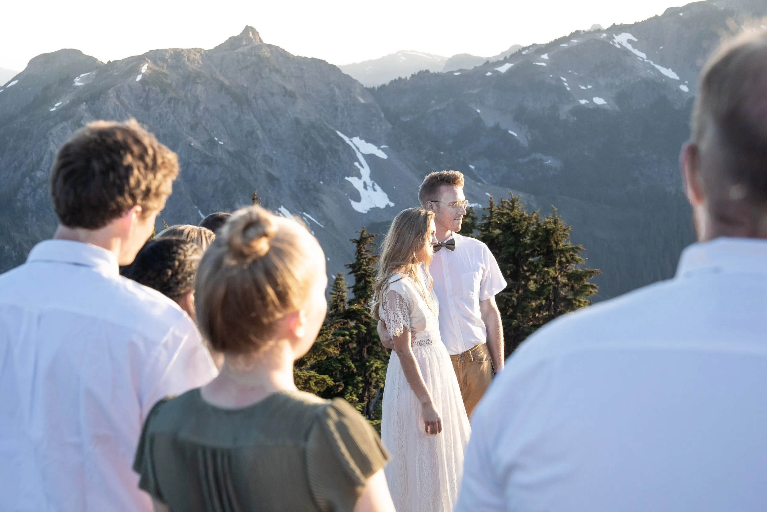 A couple holds a sunset vow exchange at High Pass in the North Cascades as their friends look on.
