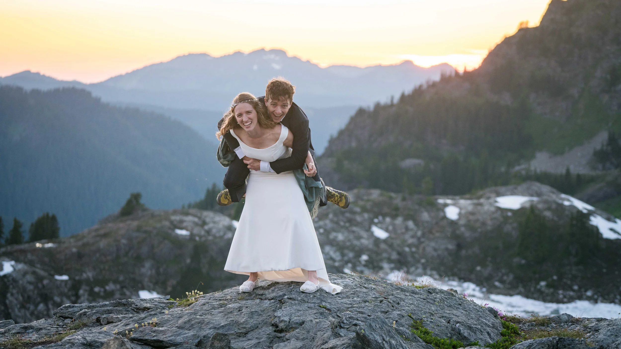 A groom jumping on a bride's back as they both laugh during a North Cascades sunset elopement at Yellow Aster Butte.