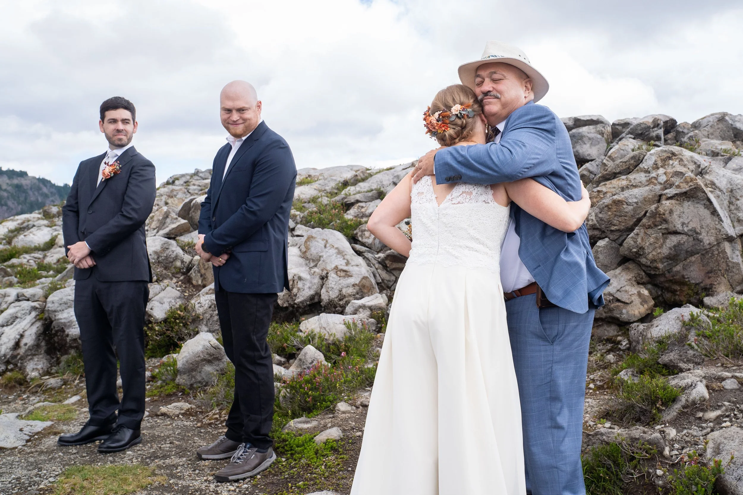 A father hugging his daughter during an elopement ceremony at Artist Point. The groom and officiant are standing to the side watching.