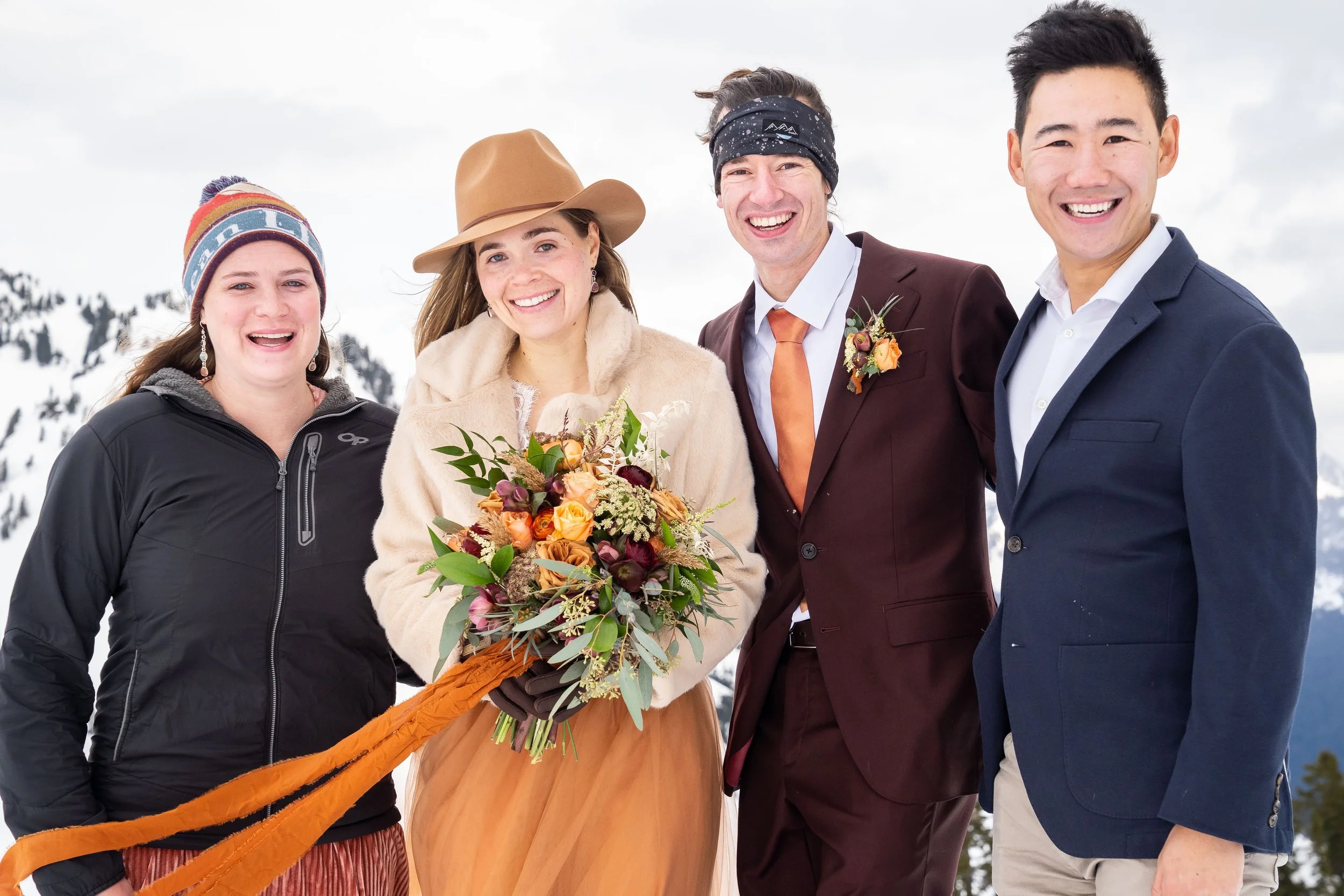 A group photo of a bride, groom, and the best man and maid of honor standing together in wedding clothes