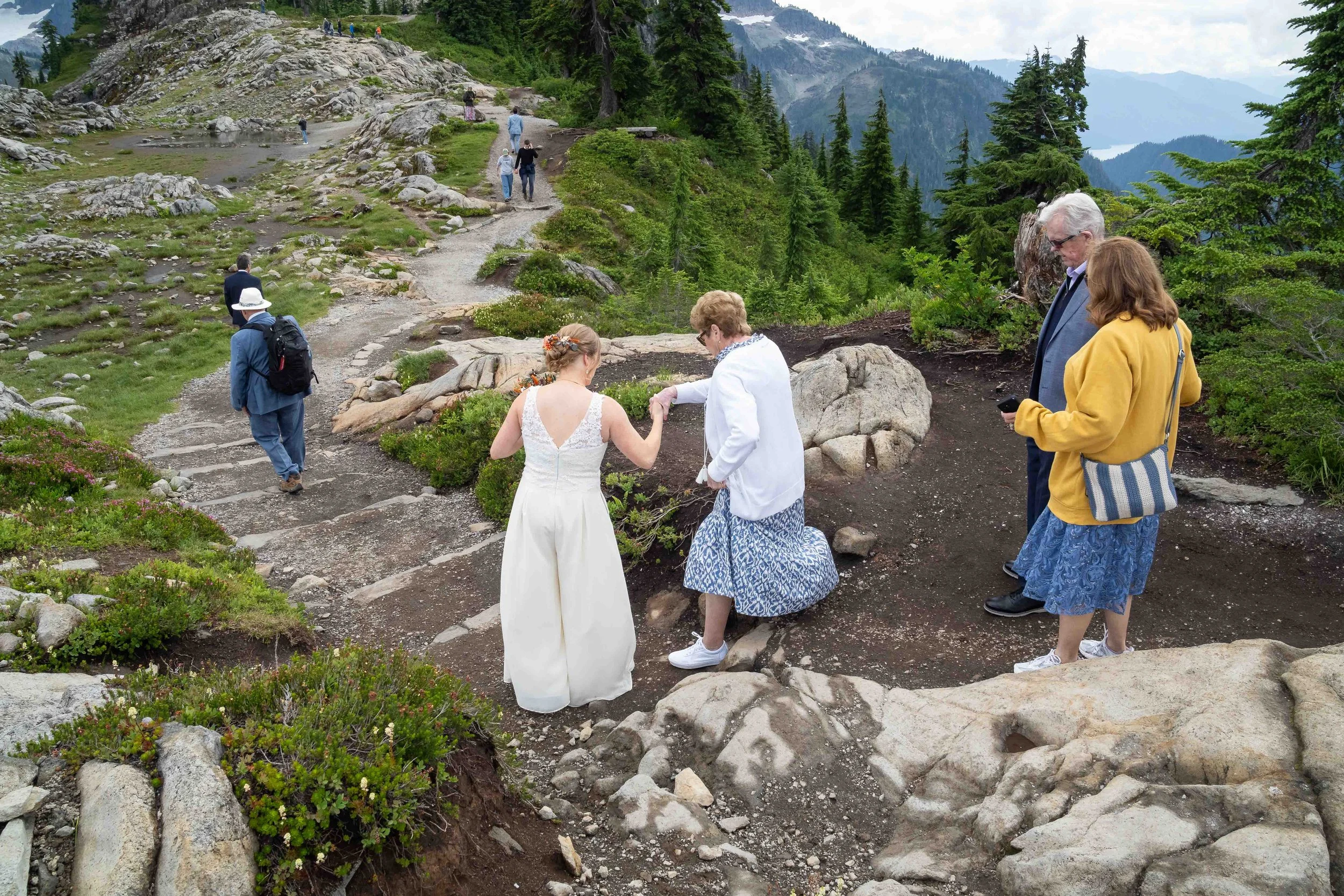 Photo of a bride helping her grandmother down the trail to an alpine meadow at Artist Point for an adventure elopement ceremony.