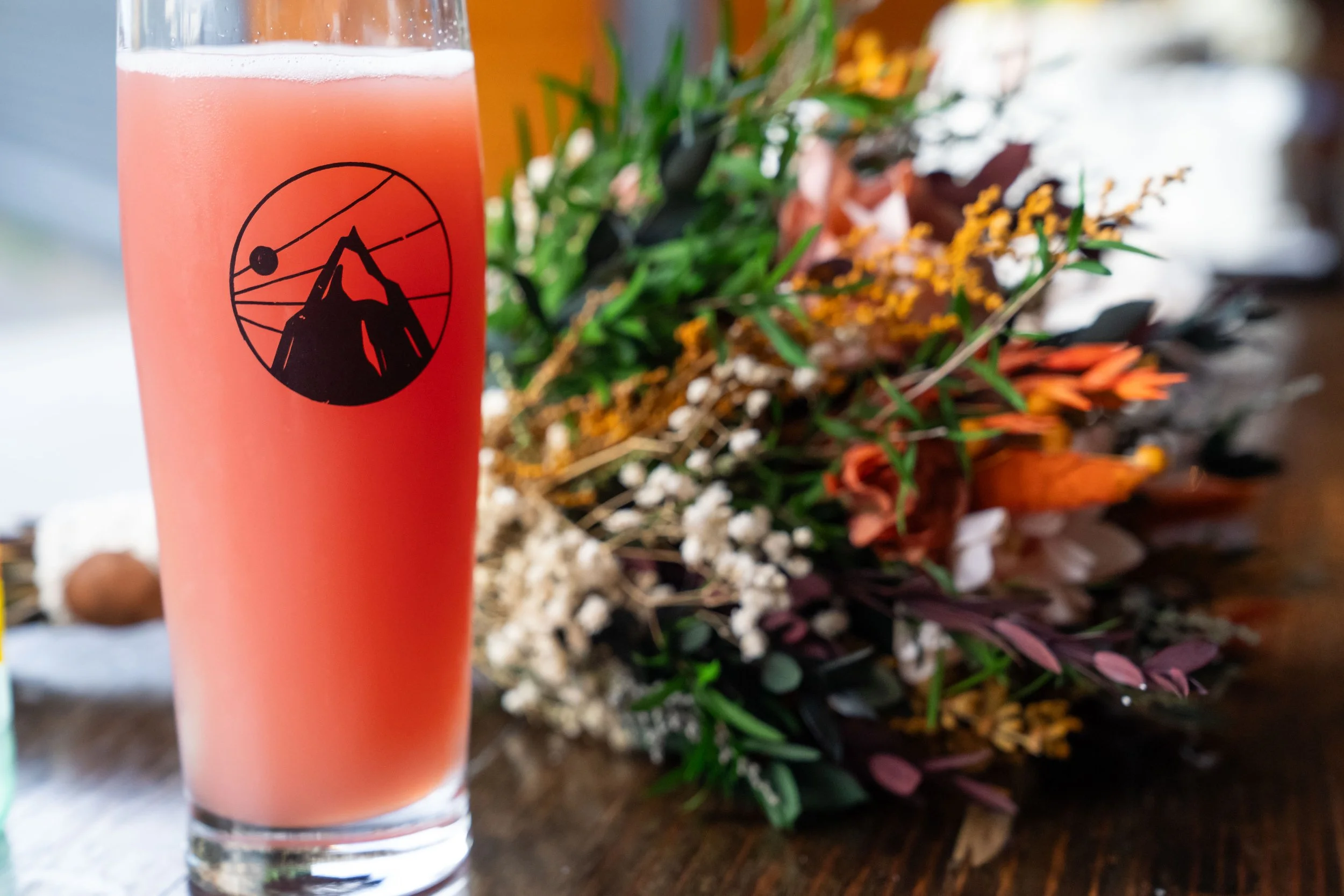 A bright red beer in a glass with the Structures Brewing logo next to a bridal bouquet during a post-elopement reception at Structures Brewing in Bellingham, Washington.