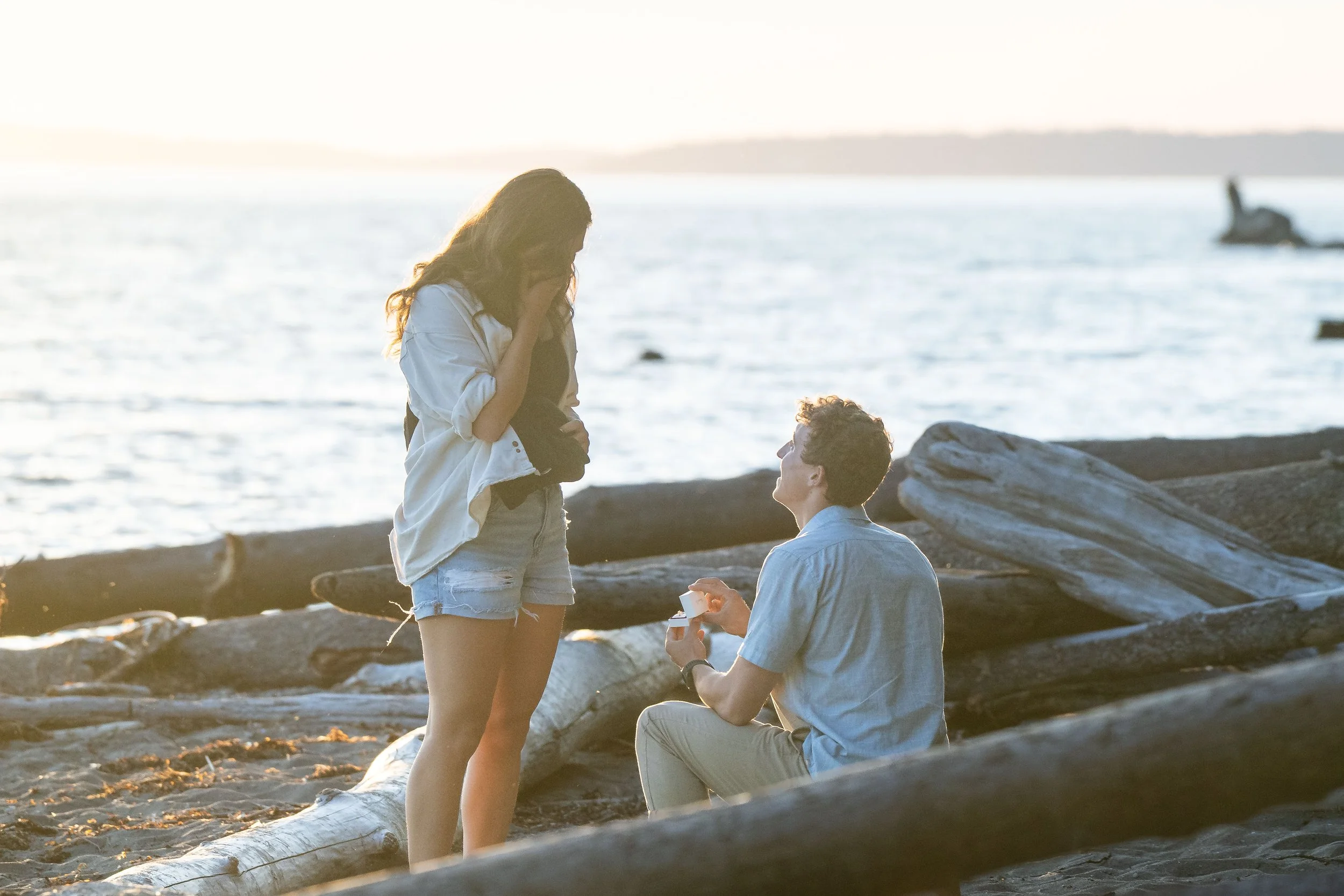 A photo of a man proposing to a woman on the beach at sunset.