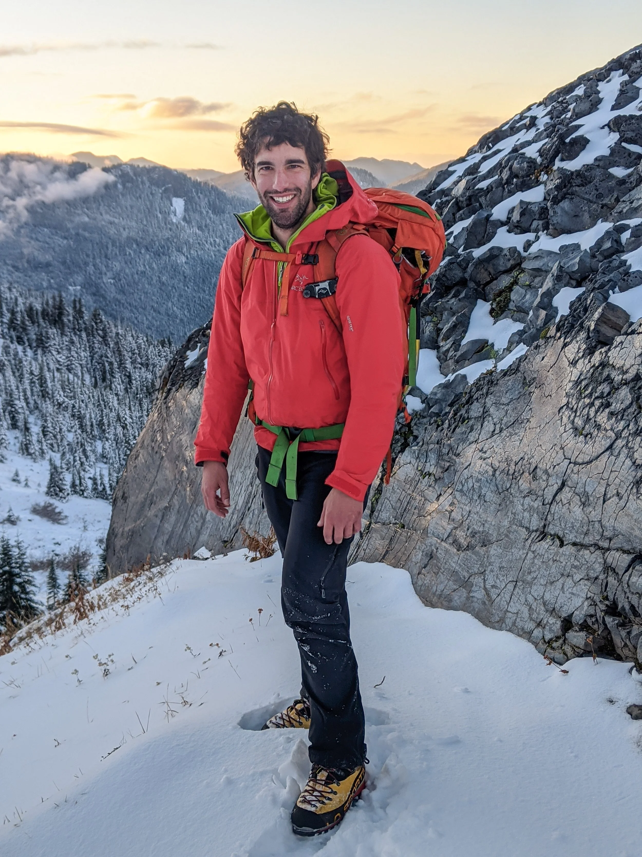 A photo of Michael, the photographer behind Wandering Sole Studios, in winter clothes with a snowy landscape and sunset behind him.