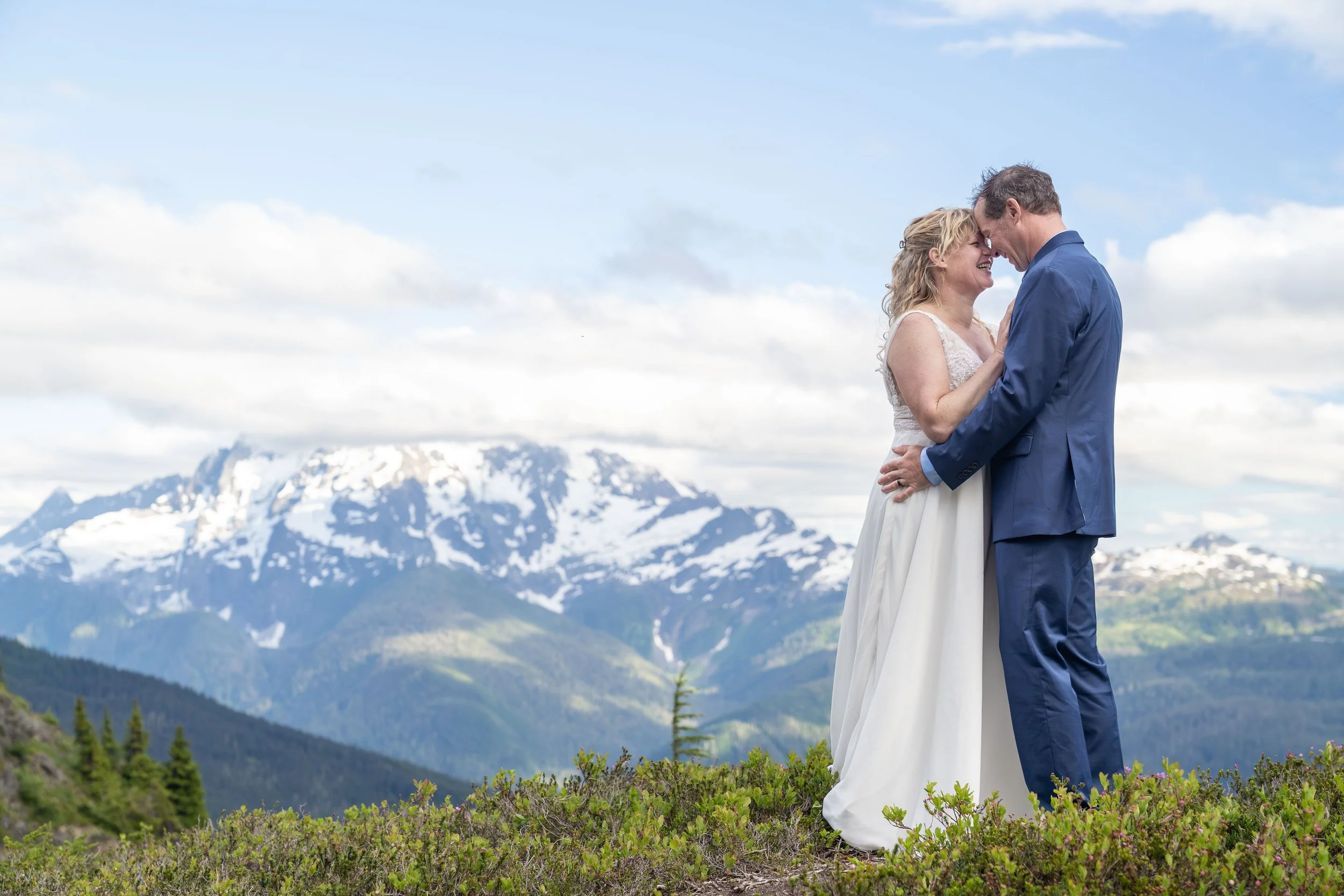 A bride and groom standing together in a subalpine meadow during their Yellow Aster Butte elopement ceremony. Mt. Shuksan is visible behind them.