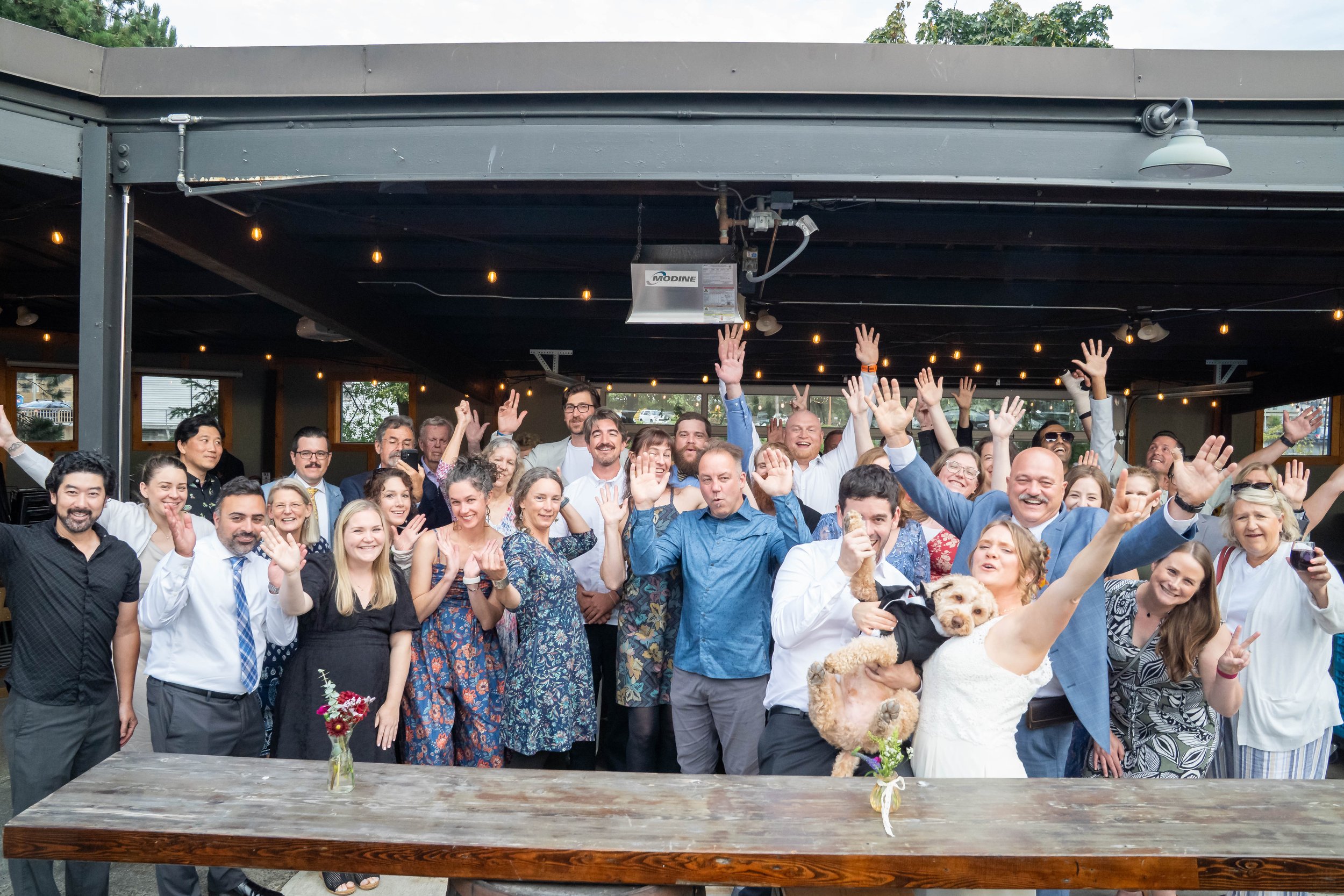 A group photo of a bride, groom, and their family and friends during a post-elopement reception at Structures Brewing in Bellingham, Washington.