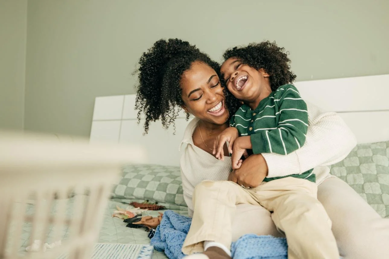 A woman holding a young boy and both laughing joyfully.