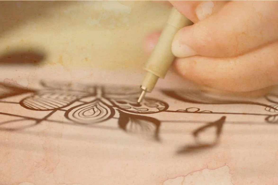 Main tenant un stylo noir, dessinant un motif floral sur une surface