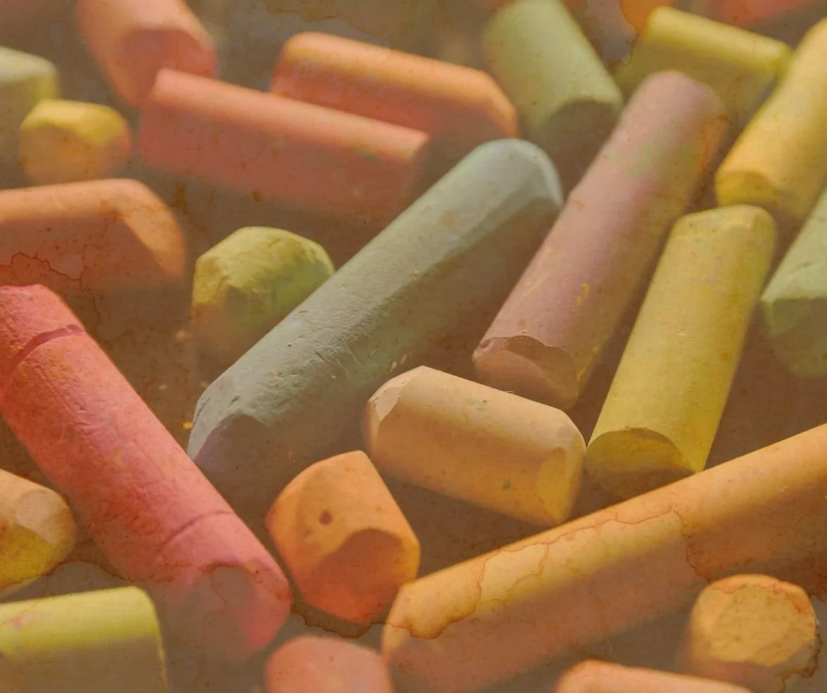 Craie de différentes couleurs, dont rose, jaune et gris, dispersée sur une surface.