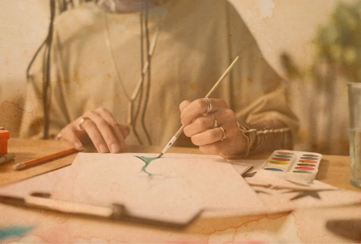 Une personne peignant une aquarelle d'une plante verte sur une feuille de papier.