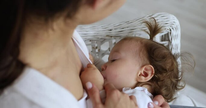 Mother breastfeeding her baby in a cozy setting.