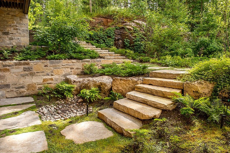 Stone steps and pathway surrounded by lush greenery in a landscaped garden.