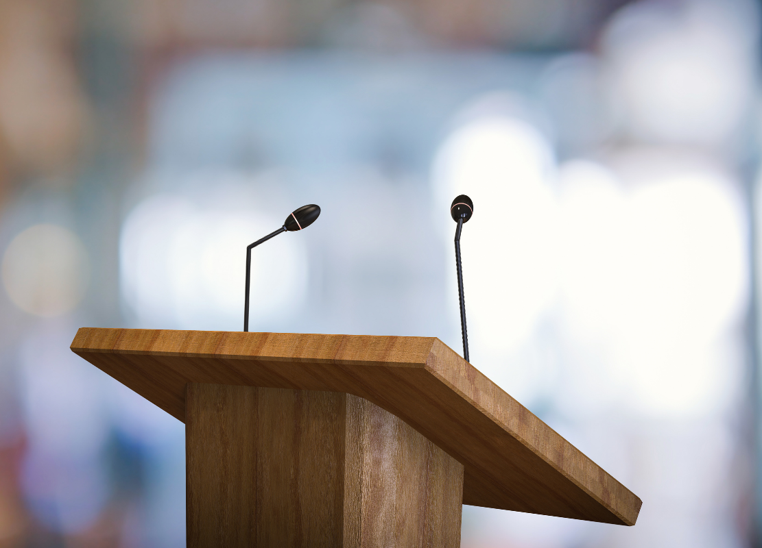 Empty wooden podium with two microphones set up for a speech or presentation.