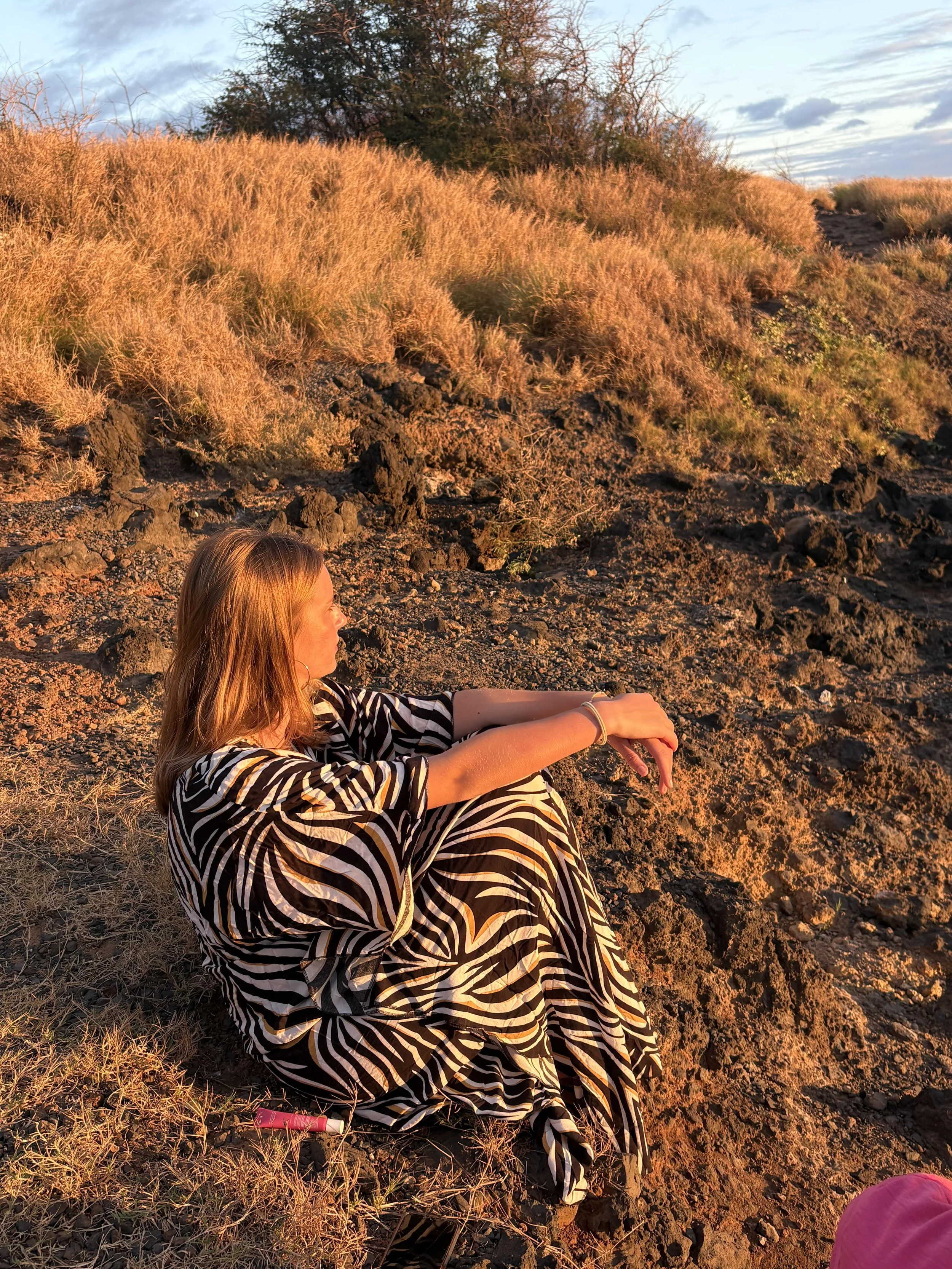 Young woman at golden hour watching sunset in Maui on a family vacation