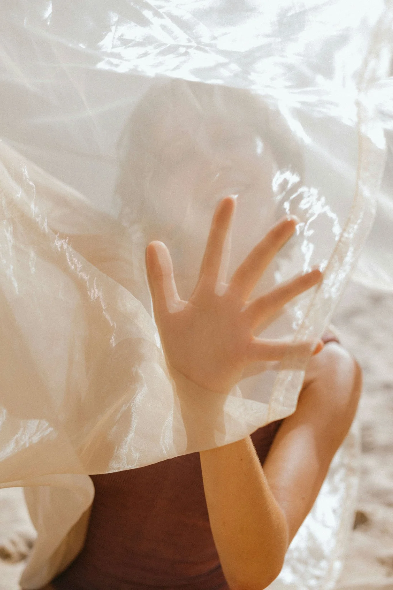 A person holding a transparent plastic bag against a light background, with a peace sign gesture made with their fingers.
