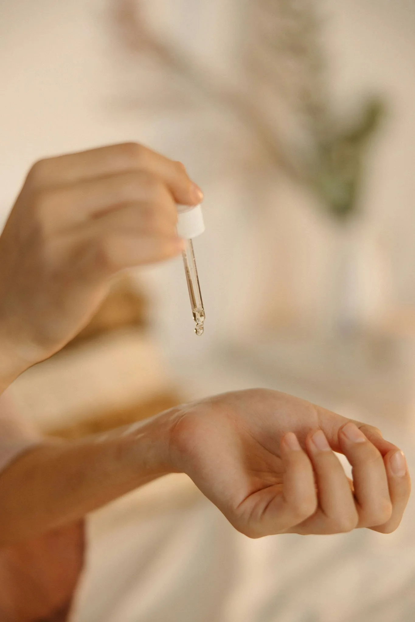 A person holding a small dropper bottle with a pipette, administering liquid onto another person's arm.