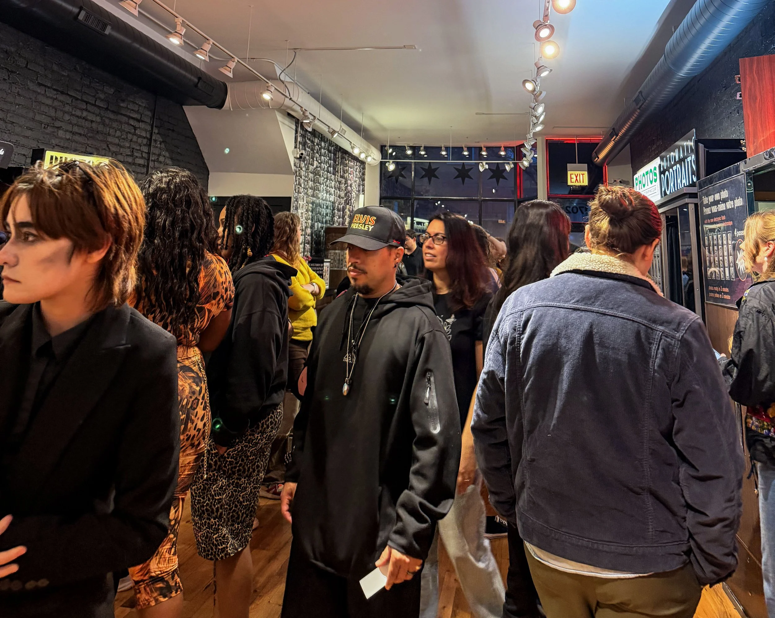 Crowd inside The Strip photobooth studio in Chicago with people waiting and moving through the space.