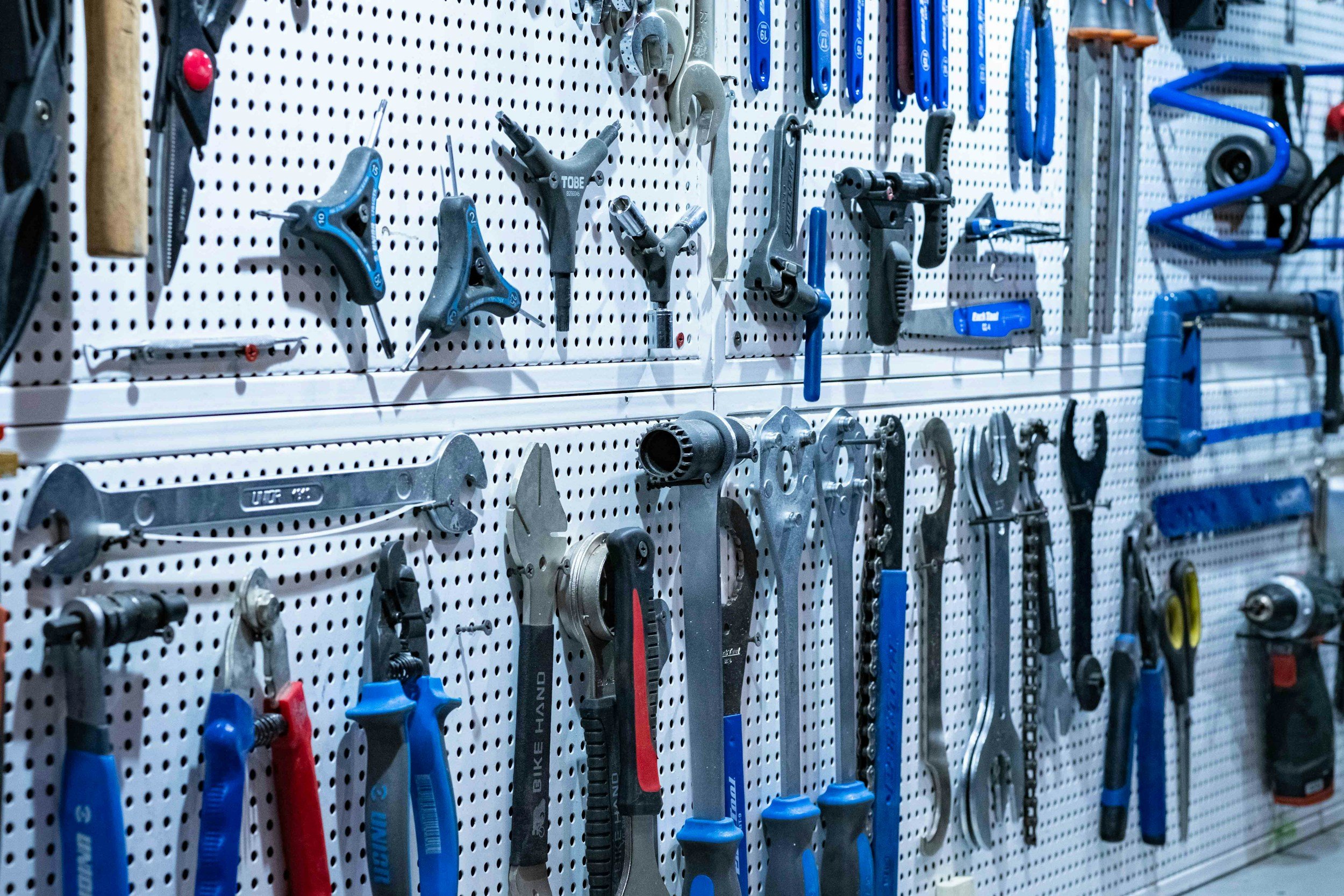 A pegboard display with various hand tools including wrenches, screwdrivers, pliers, and hammer, organized in a hardware store.