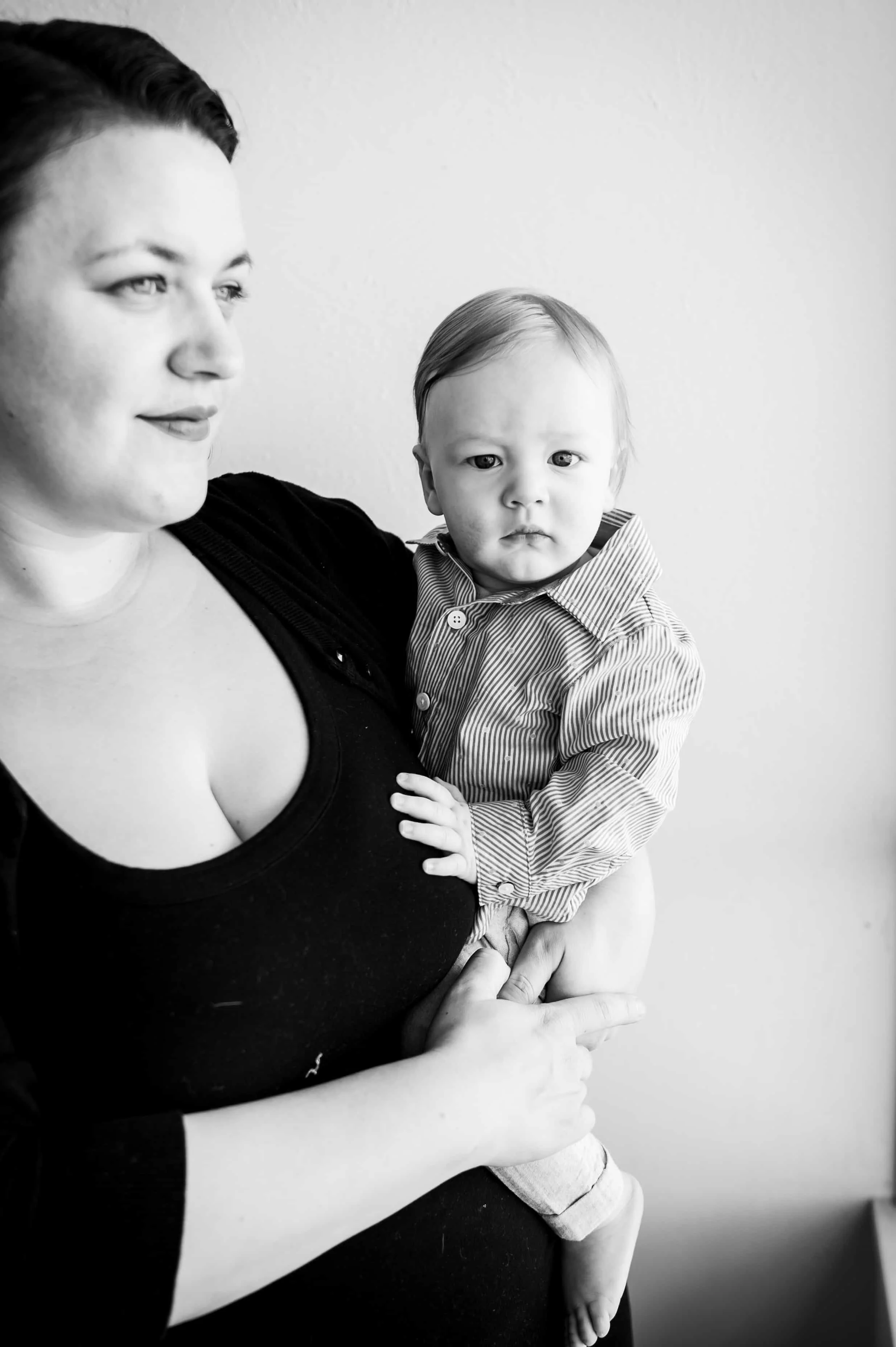 A woman holding a young child in her arms, both looking at the camera. The image is in black and white.