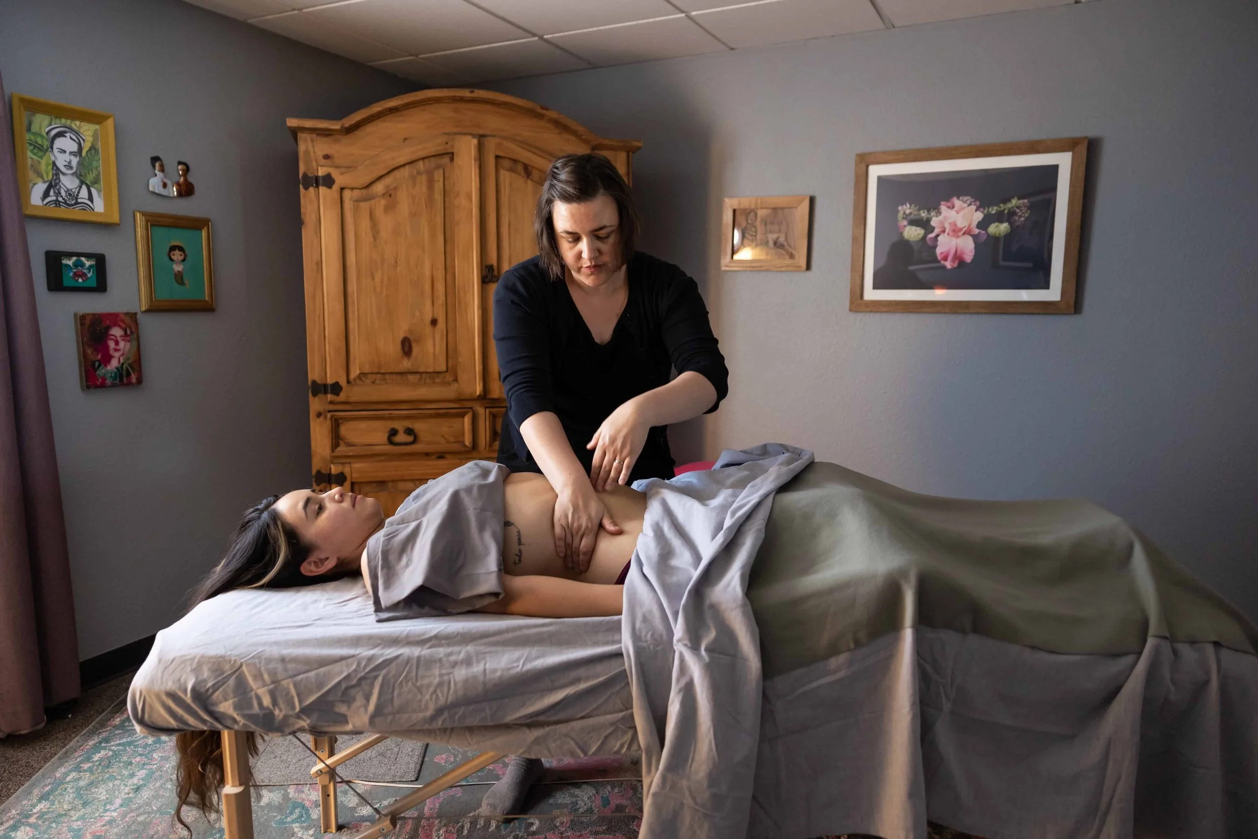 Woman giving a massage to someone on a table.