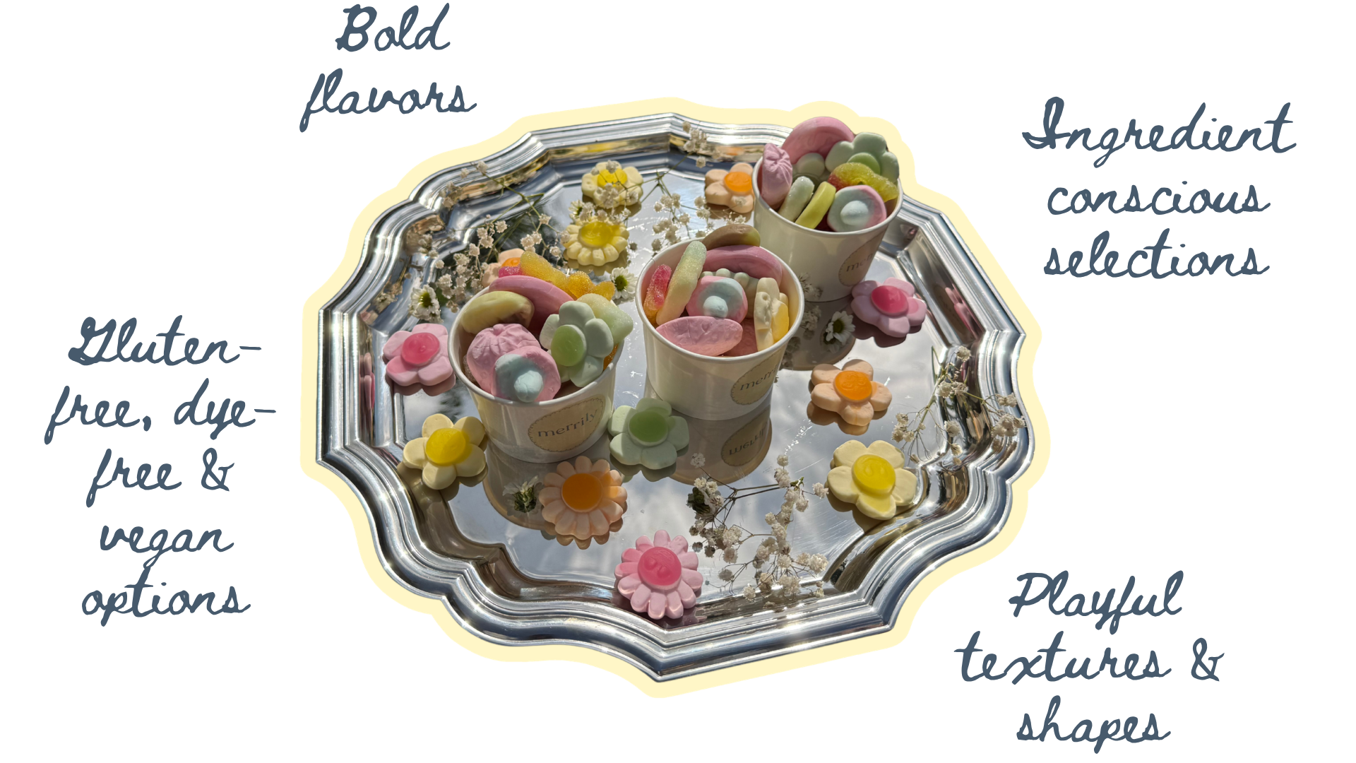 Assorted pastel-colored candies in cups and scattered on a silver tray, decorated with small white flowers.
