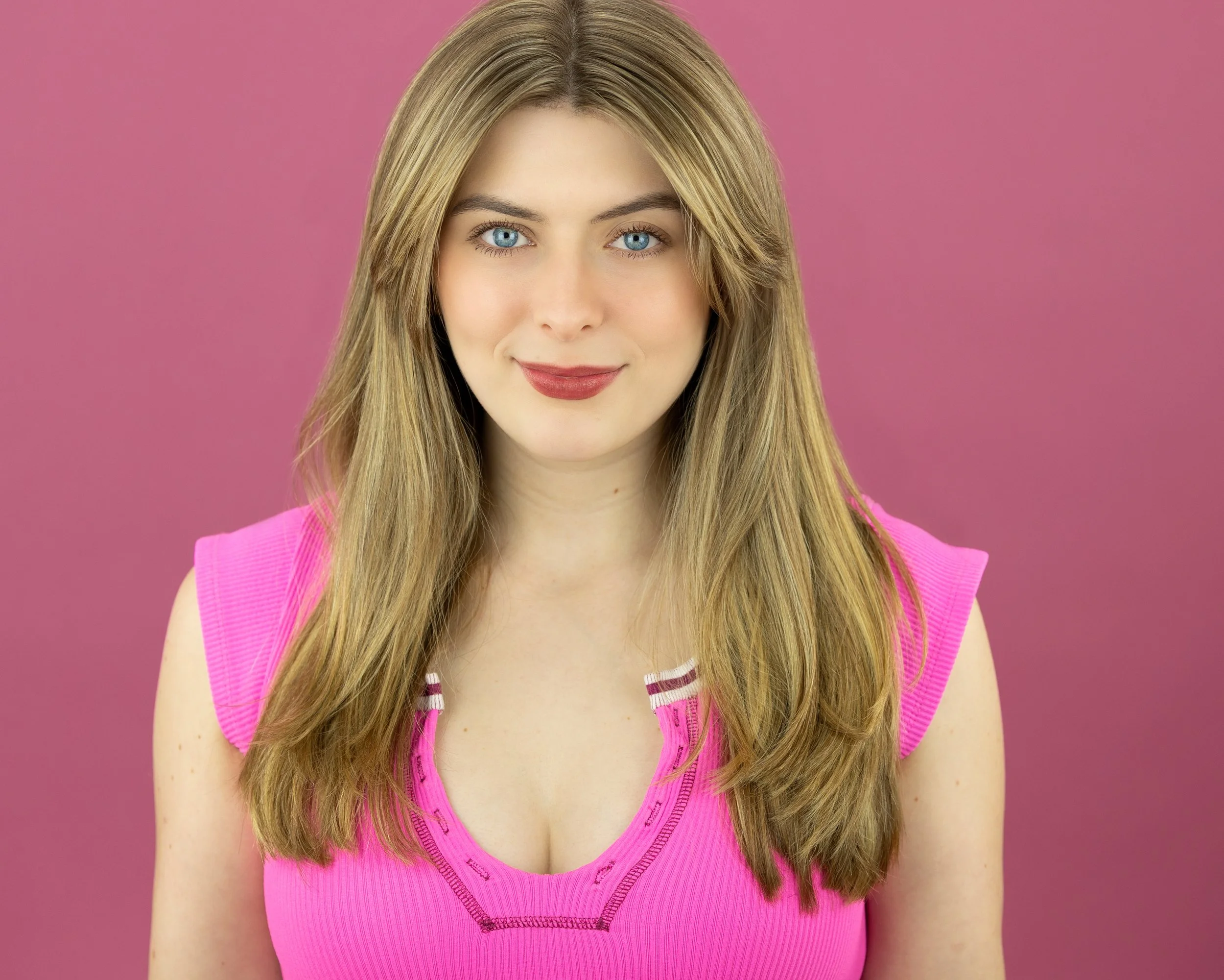 Ruby Griffin, a young actress with blonde hair and blue eyes, wearing a bright pink top against a pink background
