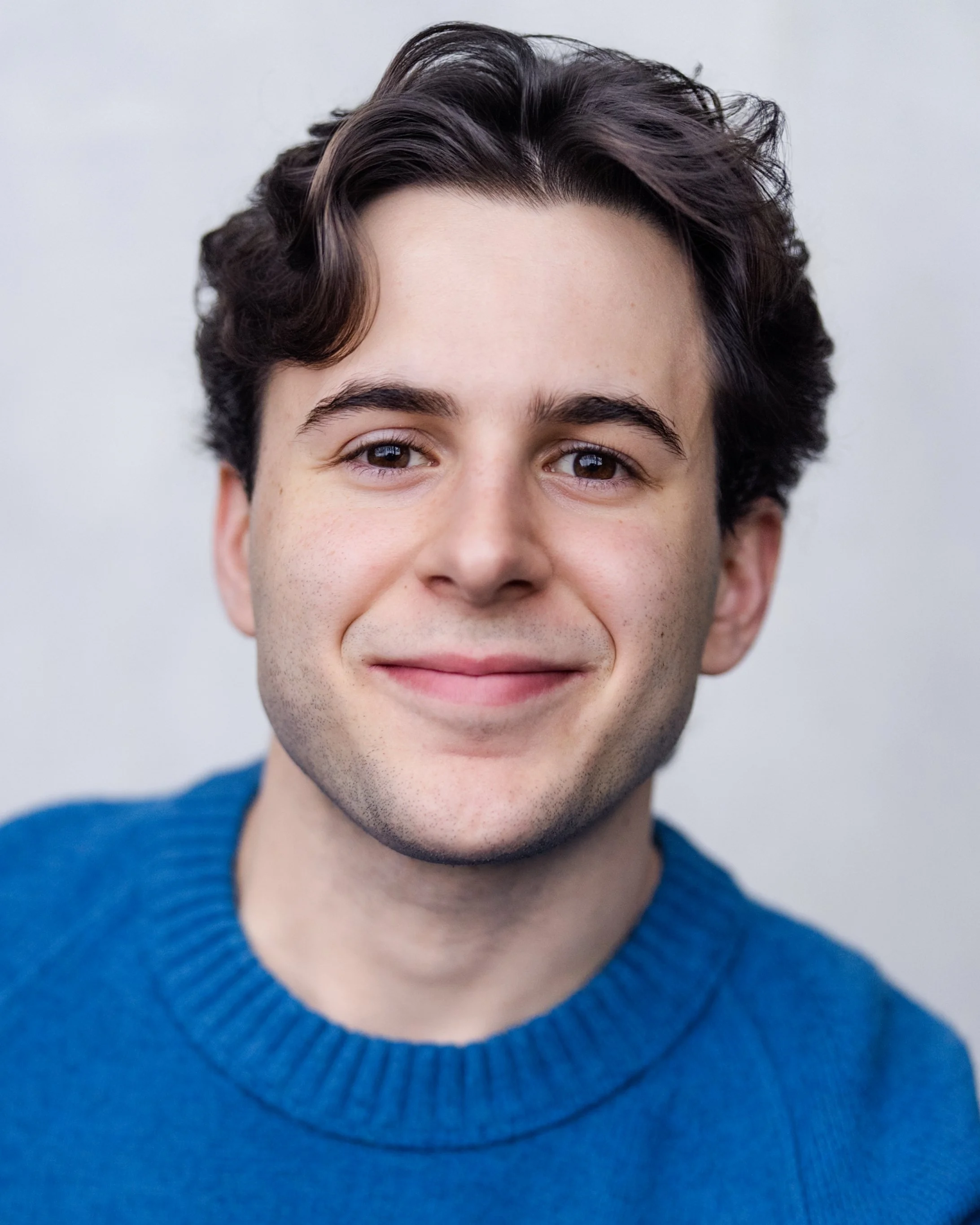 Jeremy DerMovsesian, a young actor with brown hair and brown eyes, in a bright blue sweater against a light gray backdrop