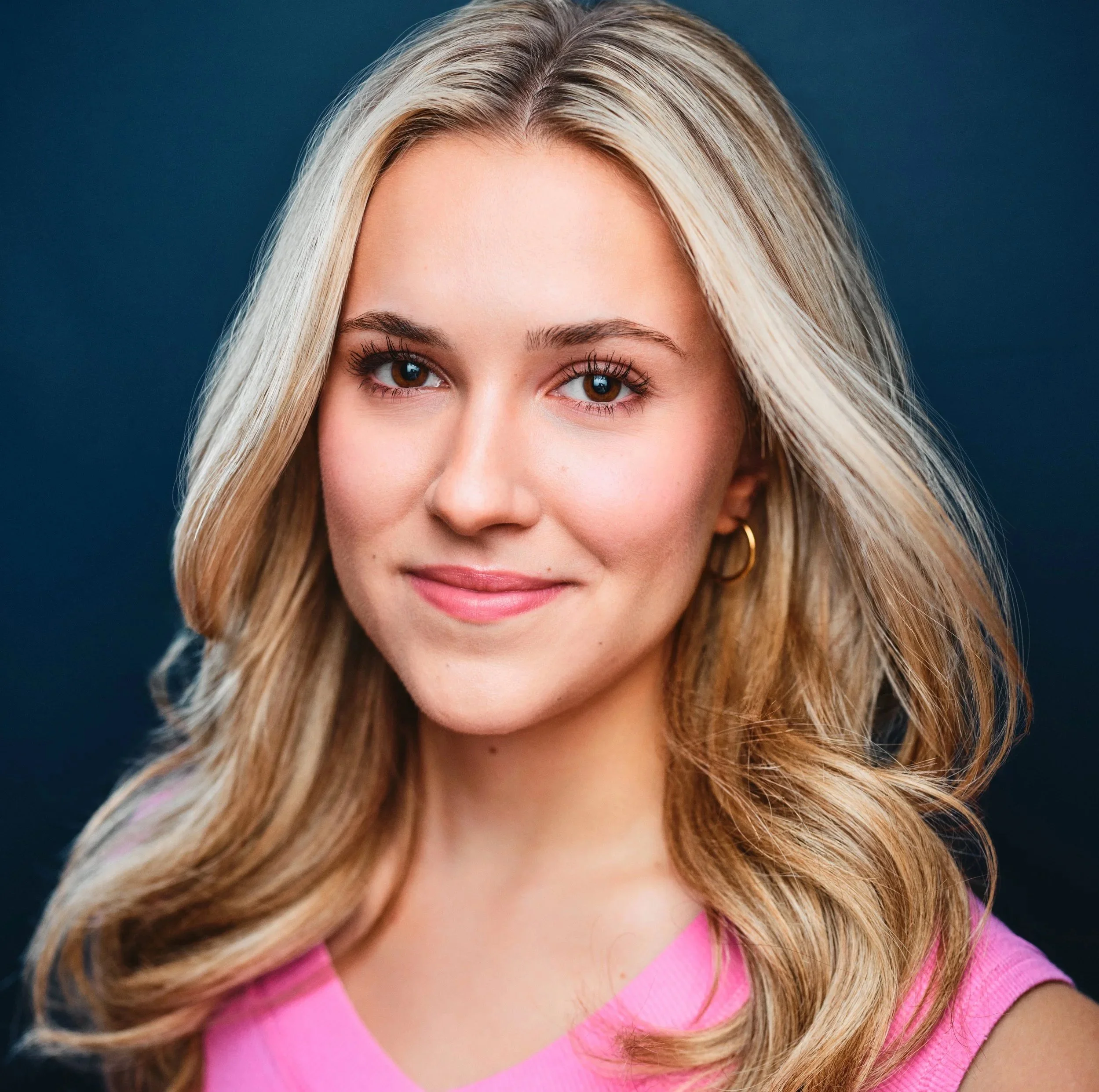 Close-up of Taylor Truckenbrod, a smiling young actress with long blonde hair wearing a pink top.