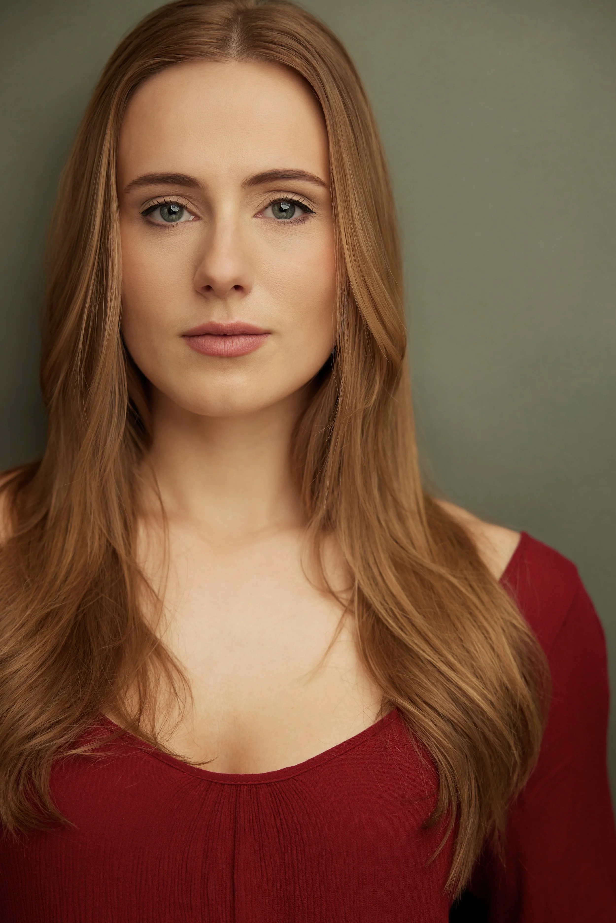 Isabella Victorson, a young actress with blonde hair and green eyes, in a dark red dress against a light green backdrop