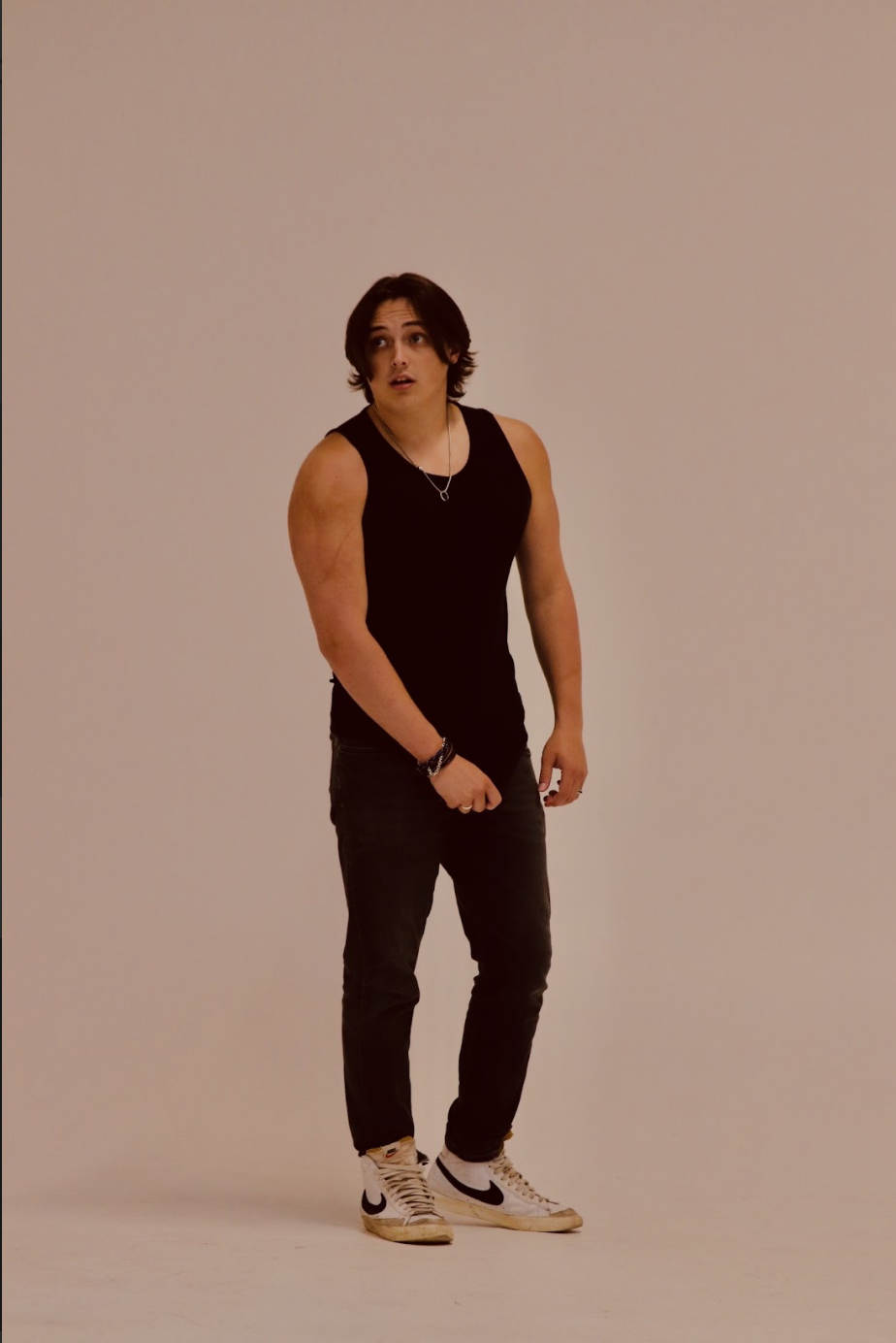 Brandon Berg, a young actor in a black tank top and black pants against a tan backdrop