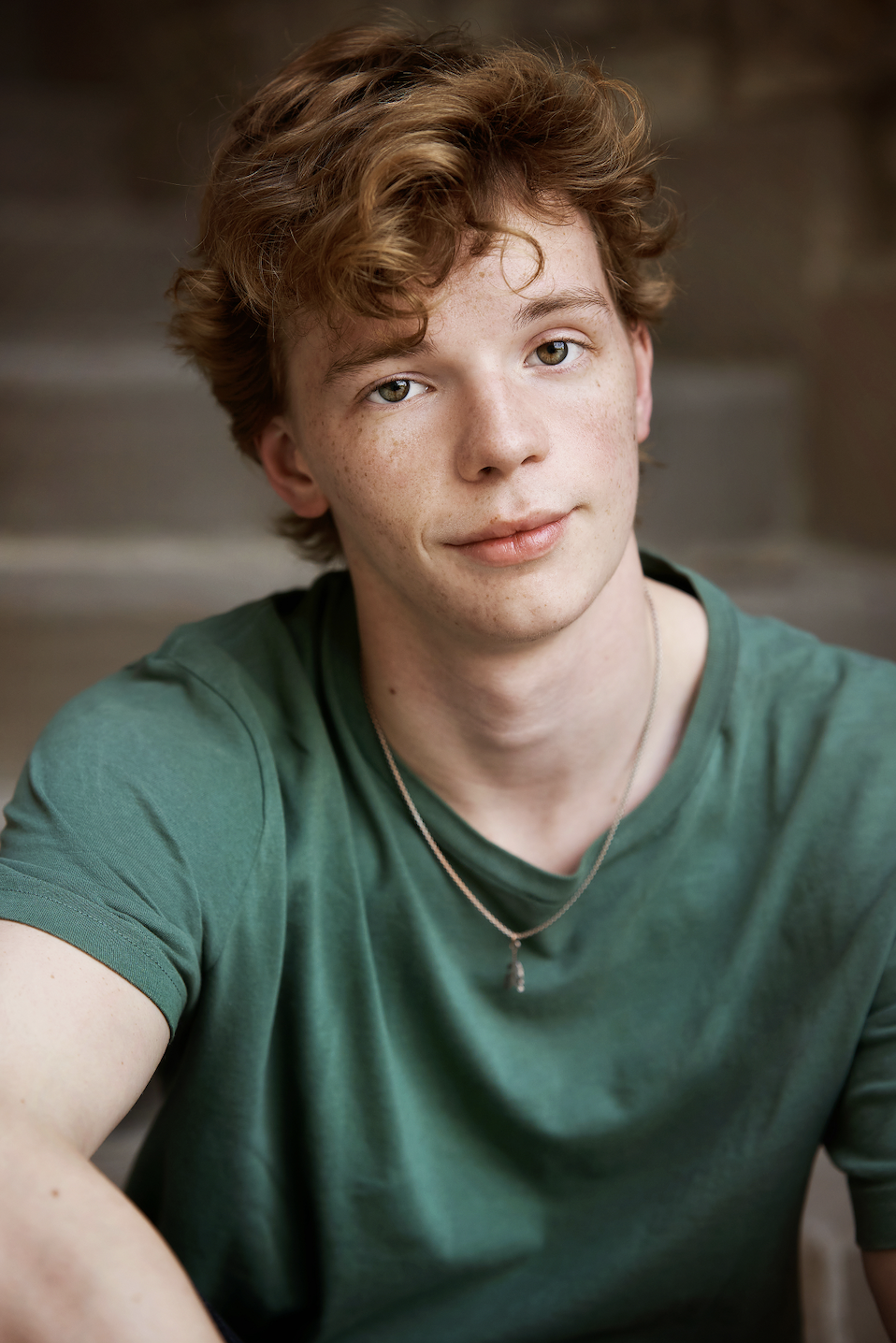 Gabriel Marcus Omlor, a young actor with red hair and hazel eyes smirking in a green tee shirt