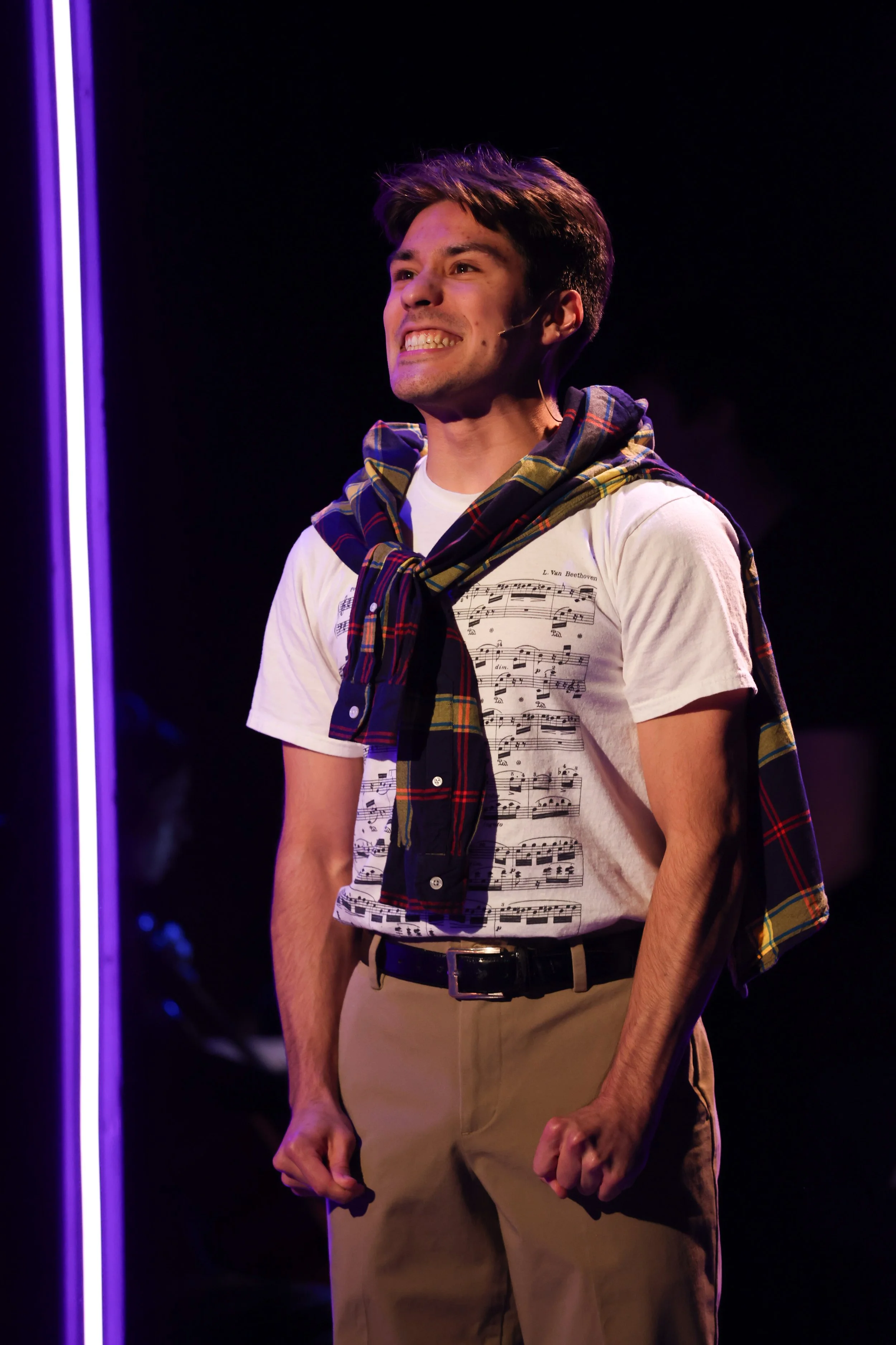 Leo Gonzalez, a young actor with dark brown hair and eyes, wearing a tee shirt with musical notes on it and a flannel over his shoulder in NSB's production of "Love Somebody Now"