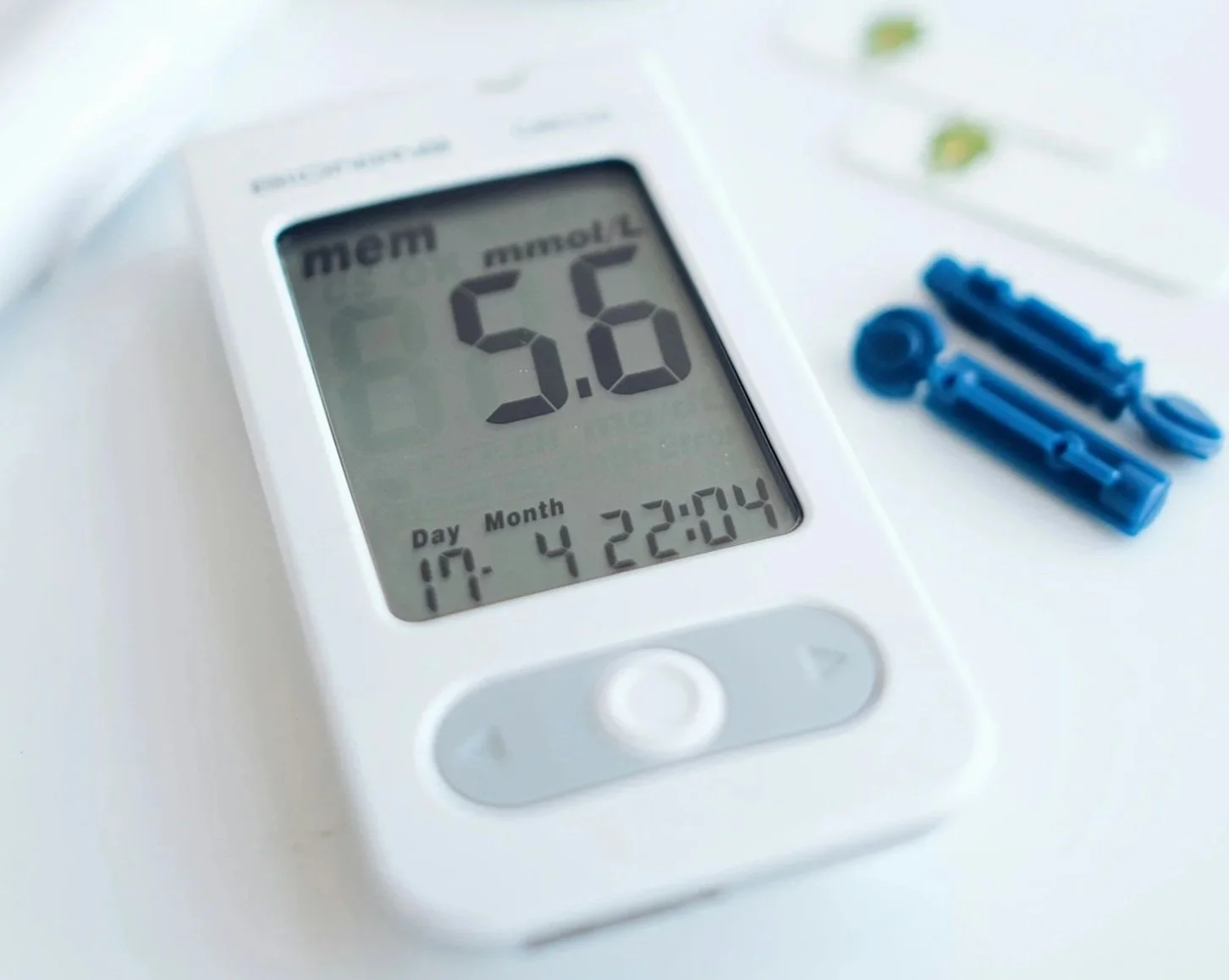 A white digital timer displaying 5.6 minutes, with the date and time below, and blue medical devices or tools beside it on a white surface.