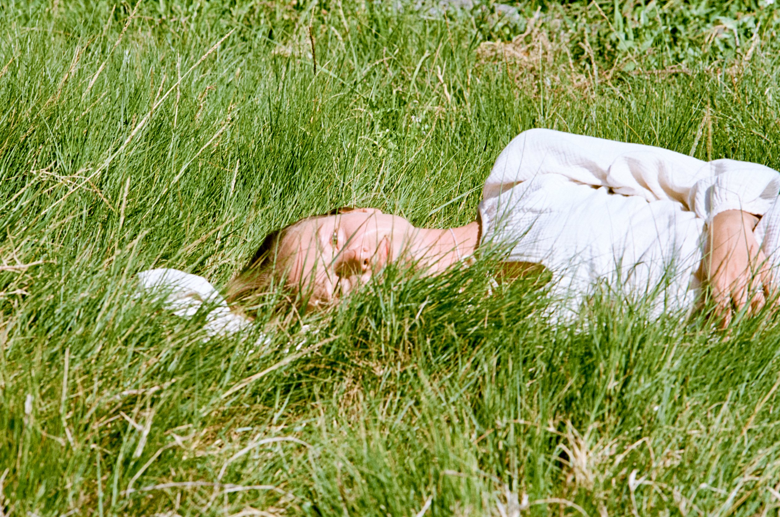 Lauren lying in tall summer grass on Yuin Country, NSW.