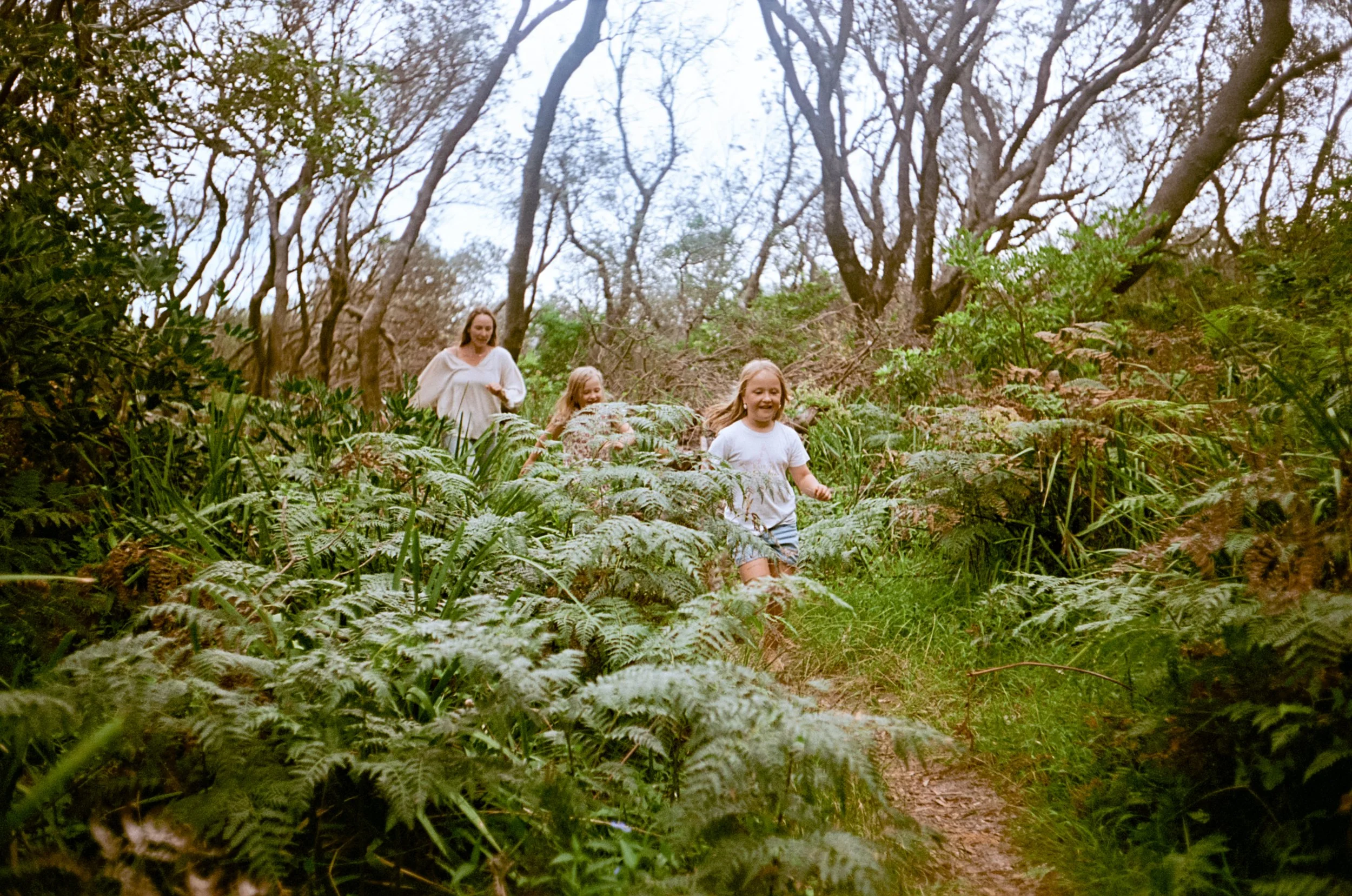 Lauren walking a bush track on Yuin Country with her two daughters.