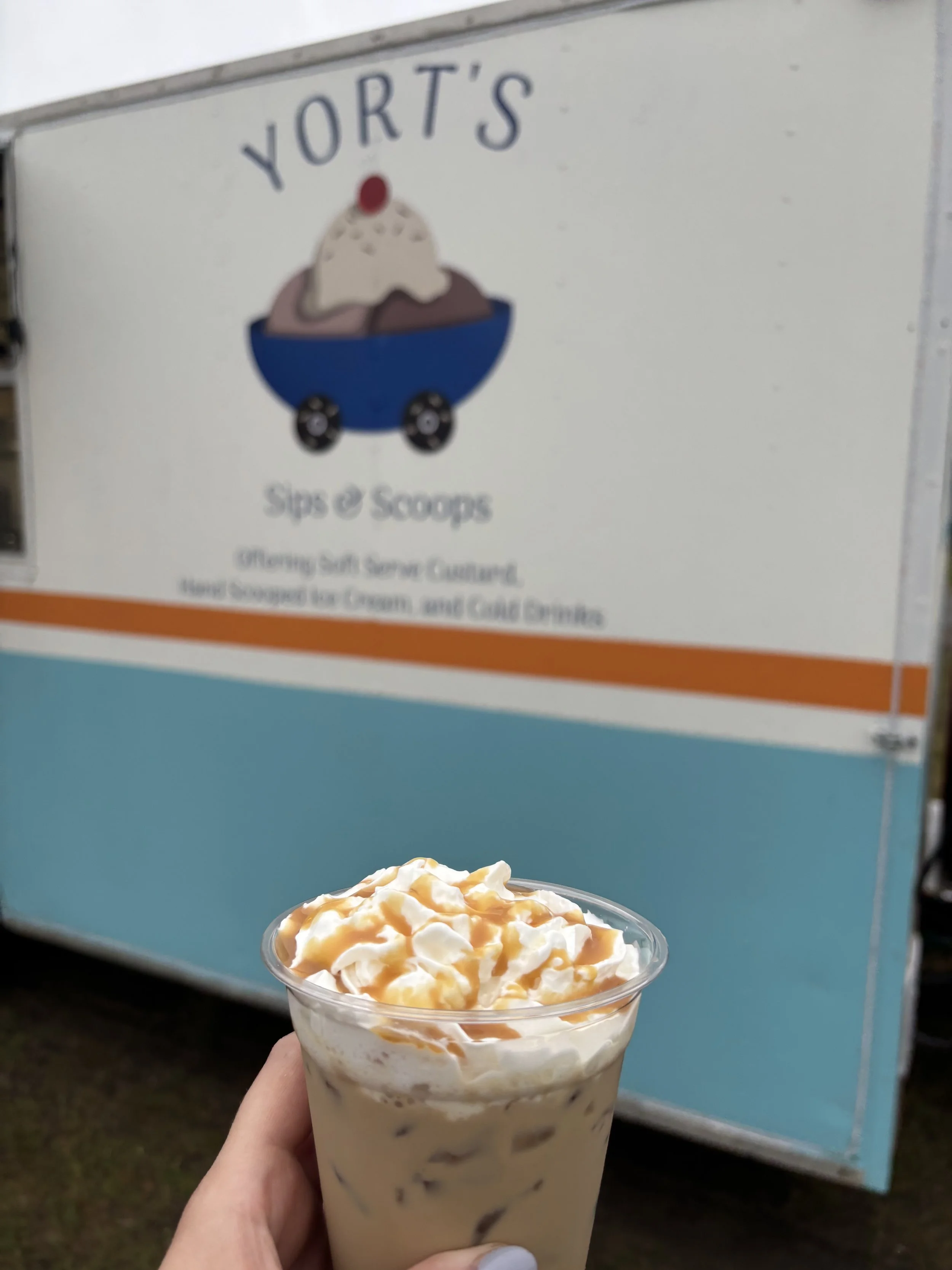 Soft serve custard with caramel topping in front of Yort’s Sips & Scoops mobile ice cream trailer in Northern Wisconsin