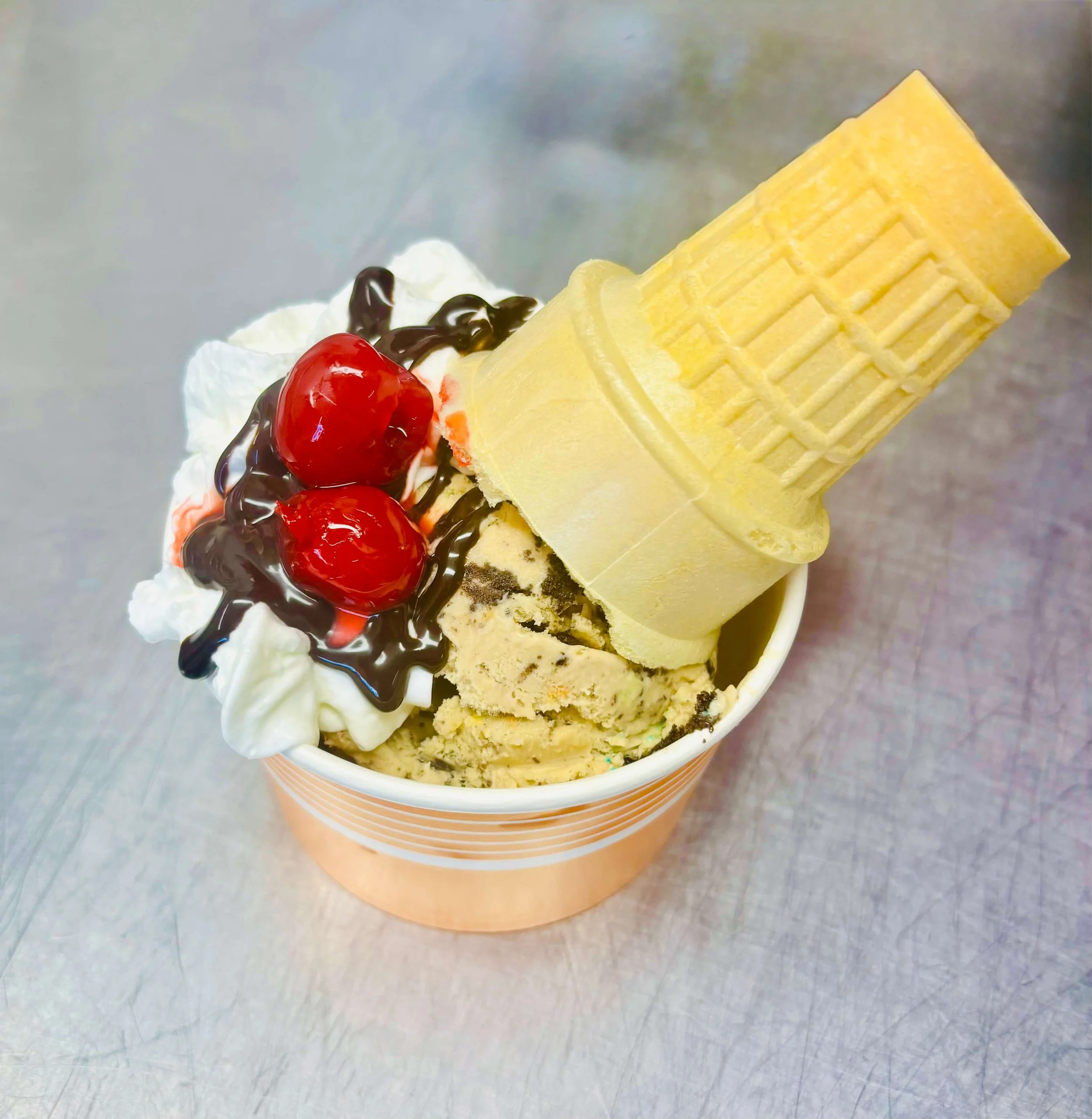 Ice cream sundae with hand-scooped ice cream, whipped cream, chocolate syrup, cherries, and a waffle cone served by a Northern Wisconsin ice cream vendor