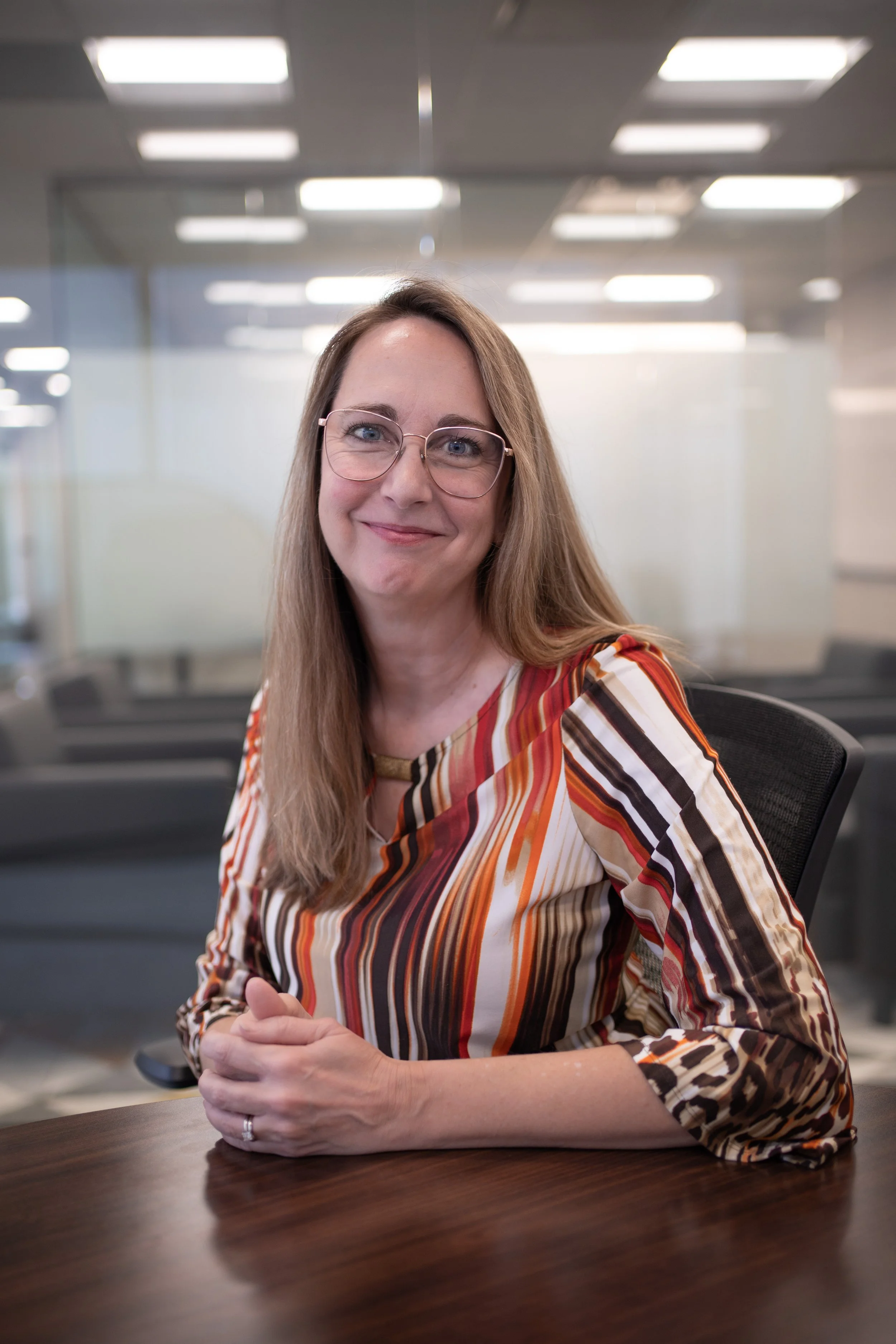 A professional headshot of Nicole Hamilton smiling at a conference table in a modern office.