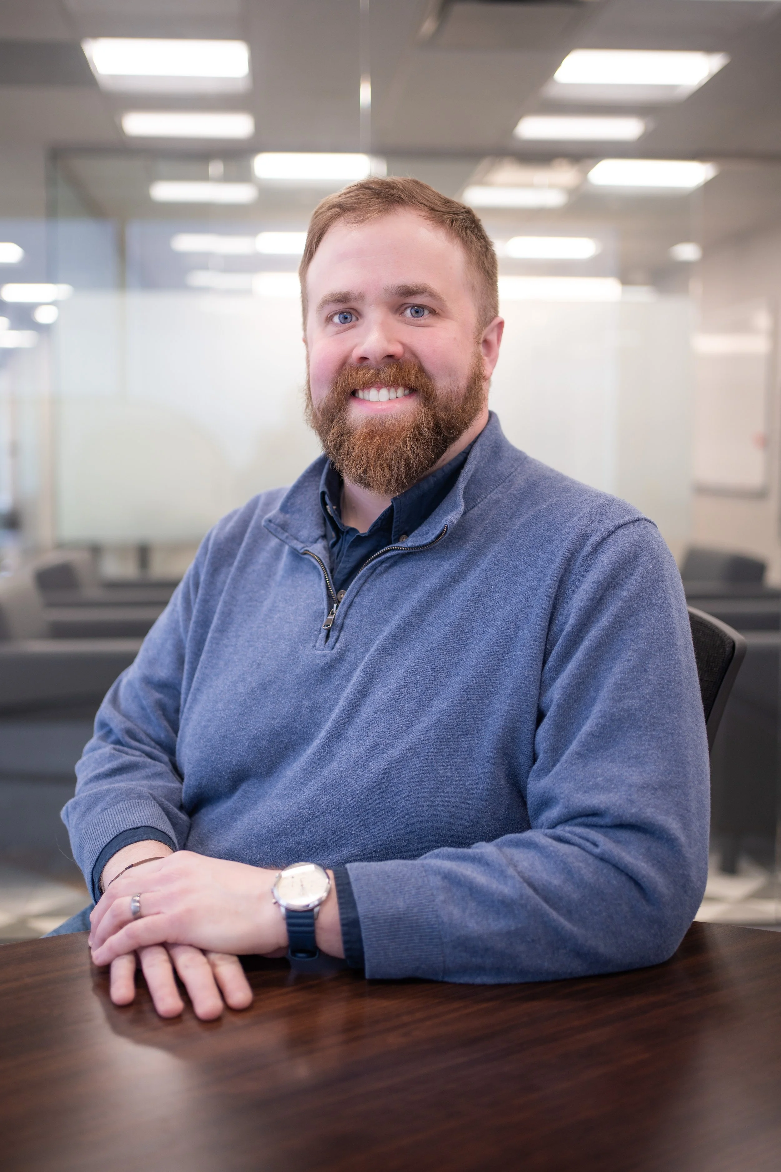 A professional headshot of Ed Smith smiling at a conference table in a modern office.