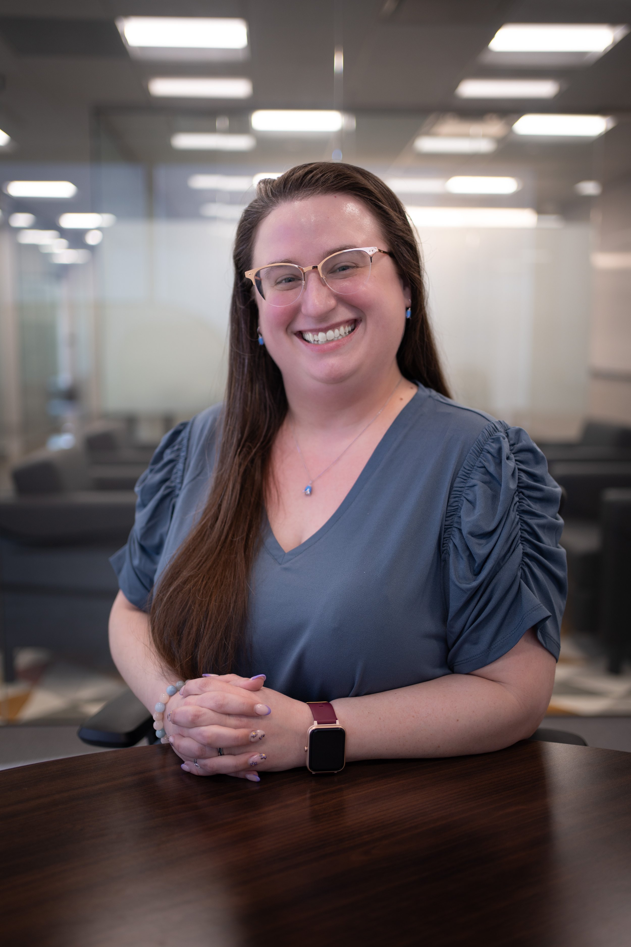 A professional headshot of Casey Carter smiling at a conference table in a modern office.